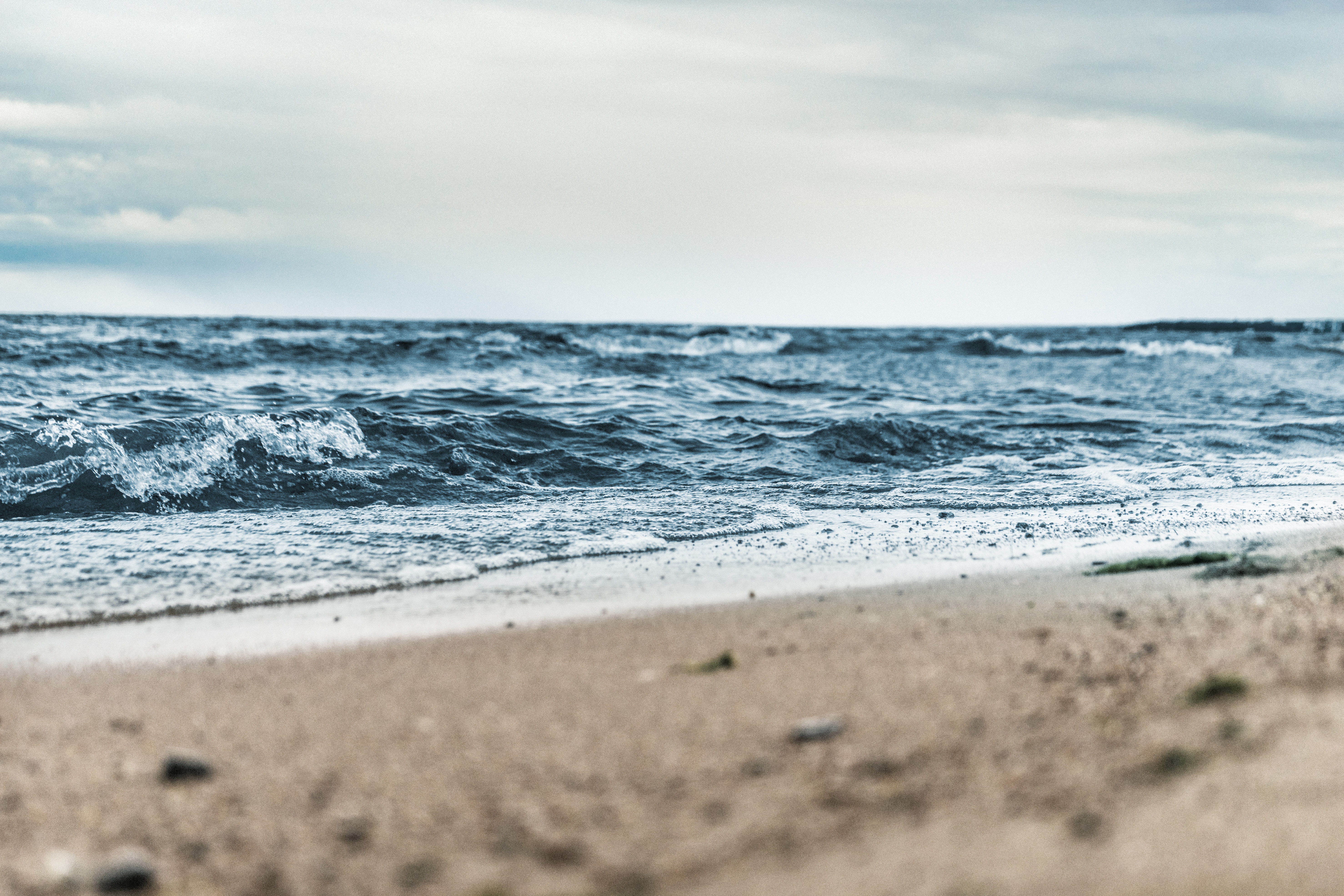 Baltic Sea waves crashing on a sandy beach under a cloudy sky HD Wallpaper