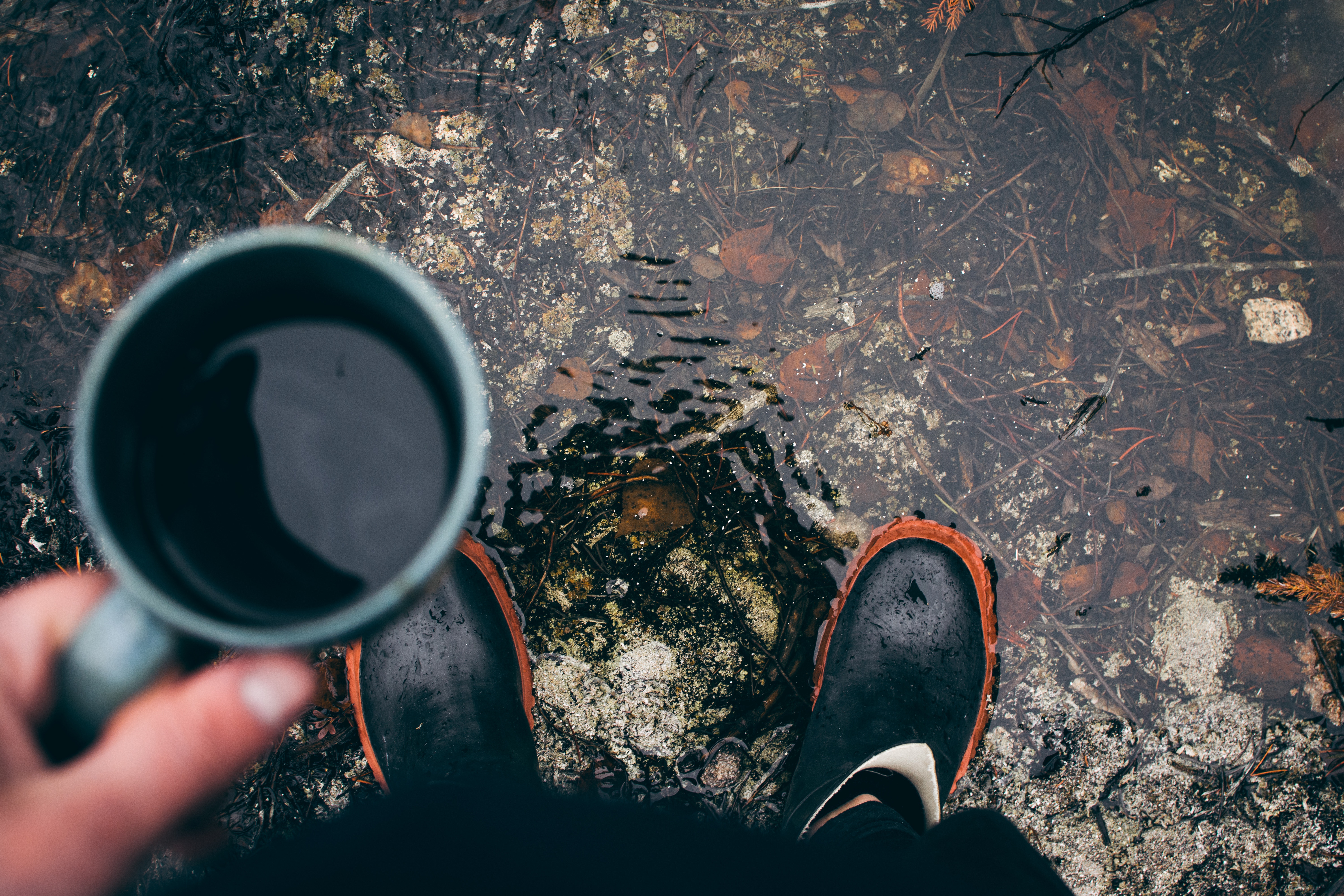 Person holding coffee cup standing in puddle with boots HD Wallpaper