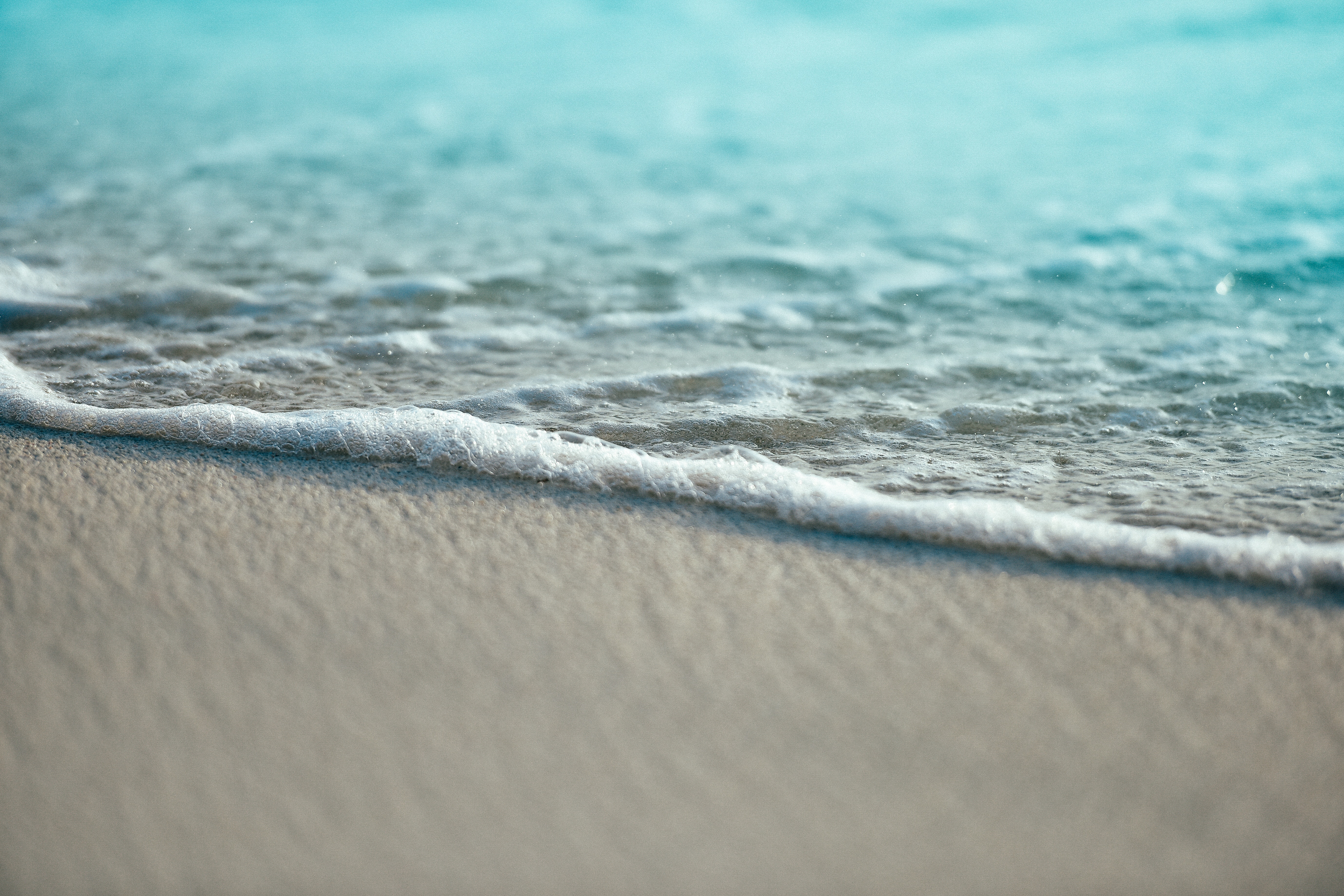 Gentle waves lap onto a sandy beach HD Wallpaper