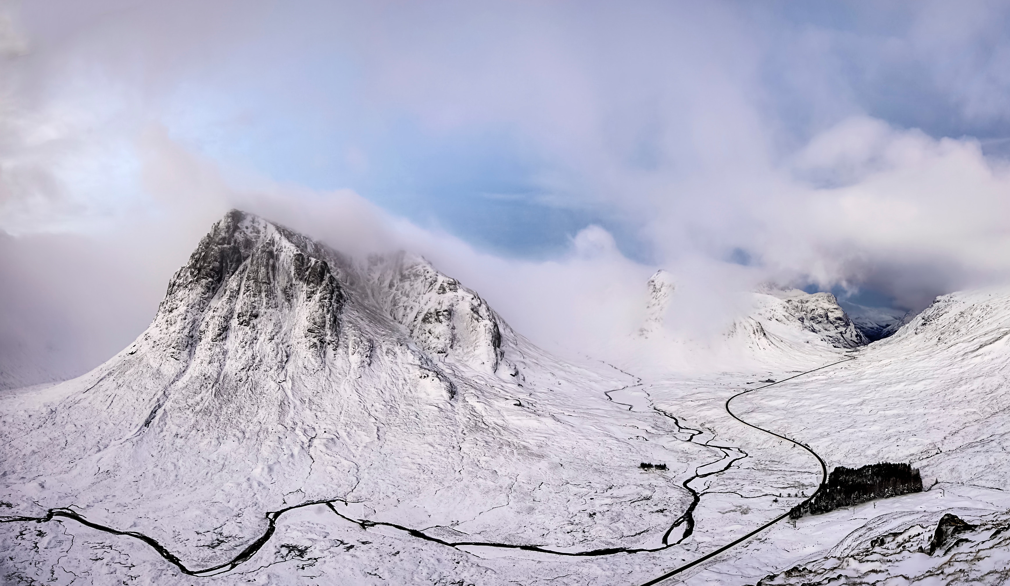 Snowy mountain valley with a winding road and clouds HD Wallpaper