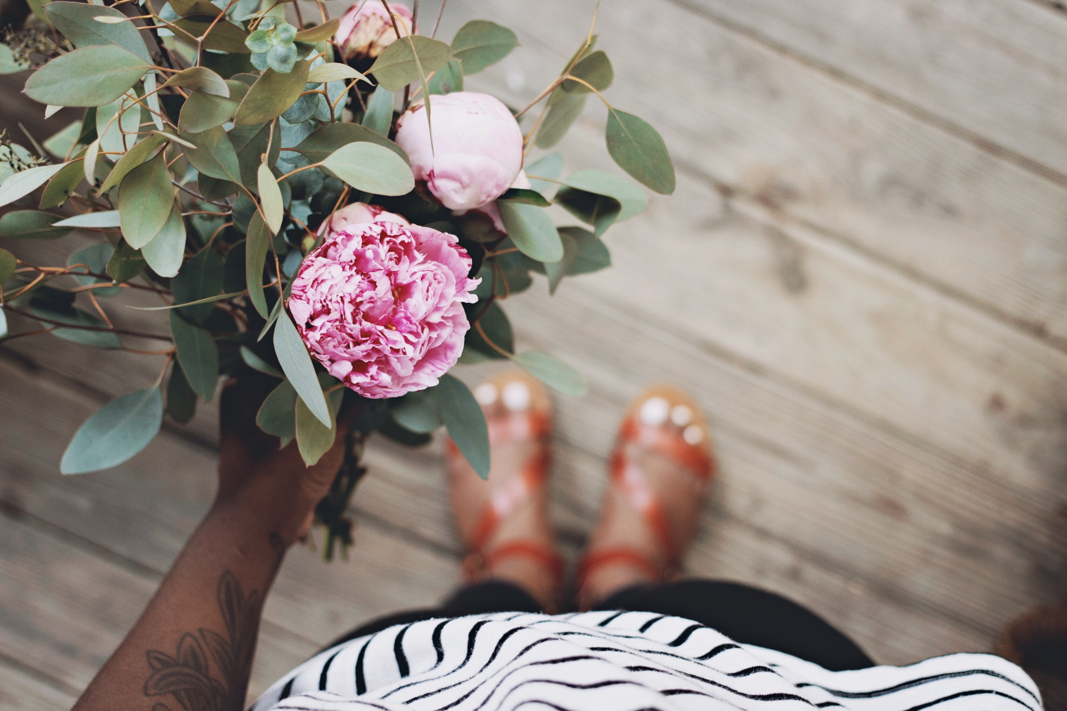 Person holding a pink peony bouquet on wooden flooring HD Wallpaper