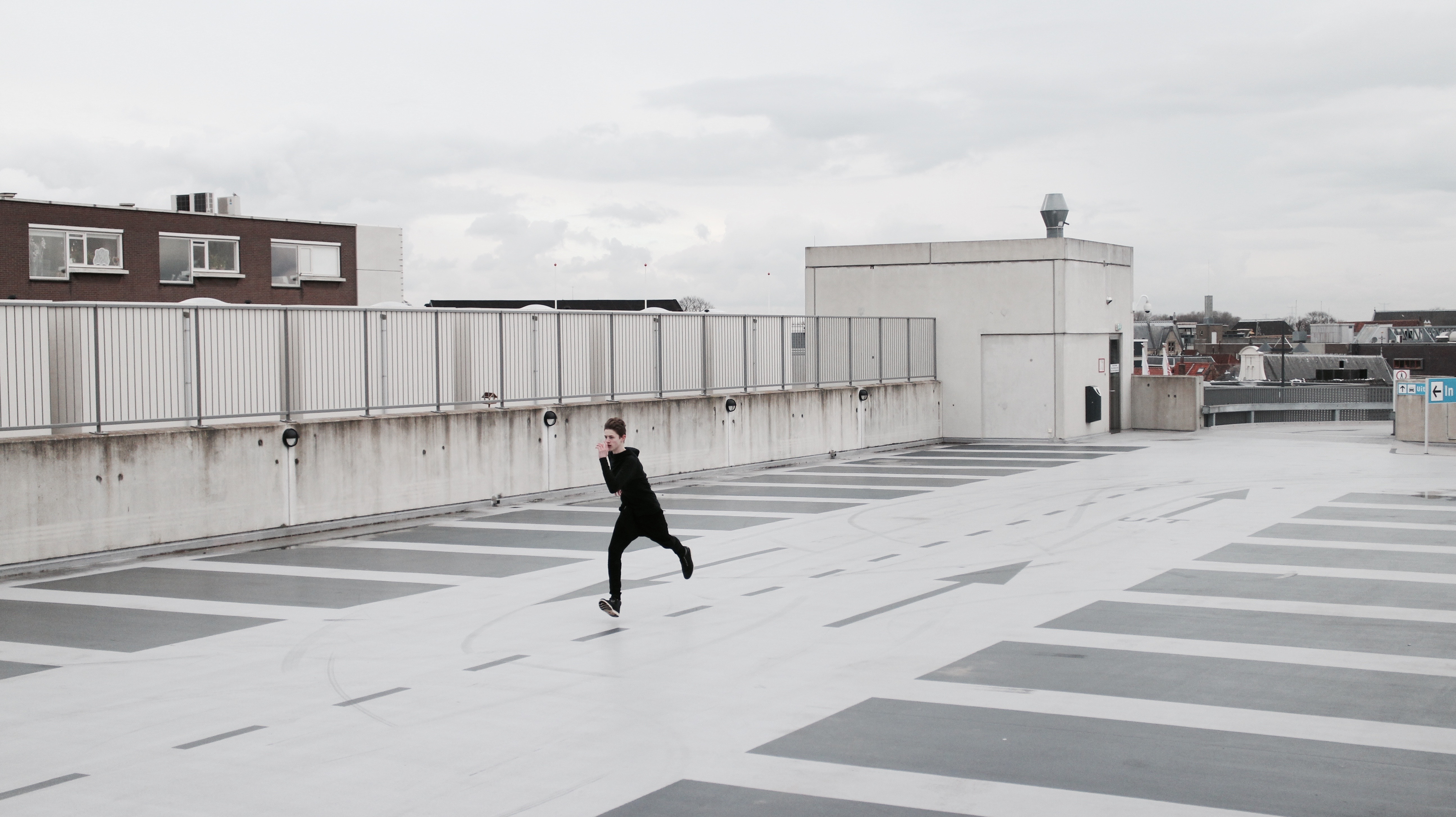A person running on a concrete rooftop parking lot HD Wallpaper