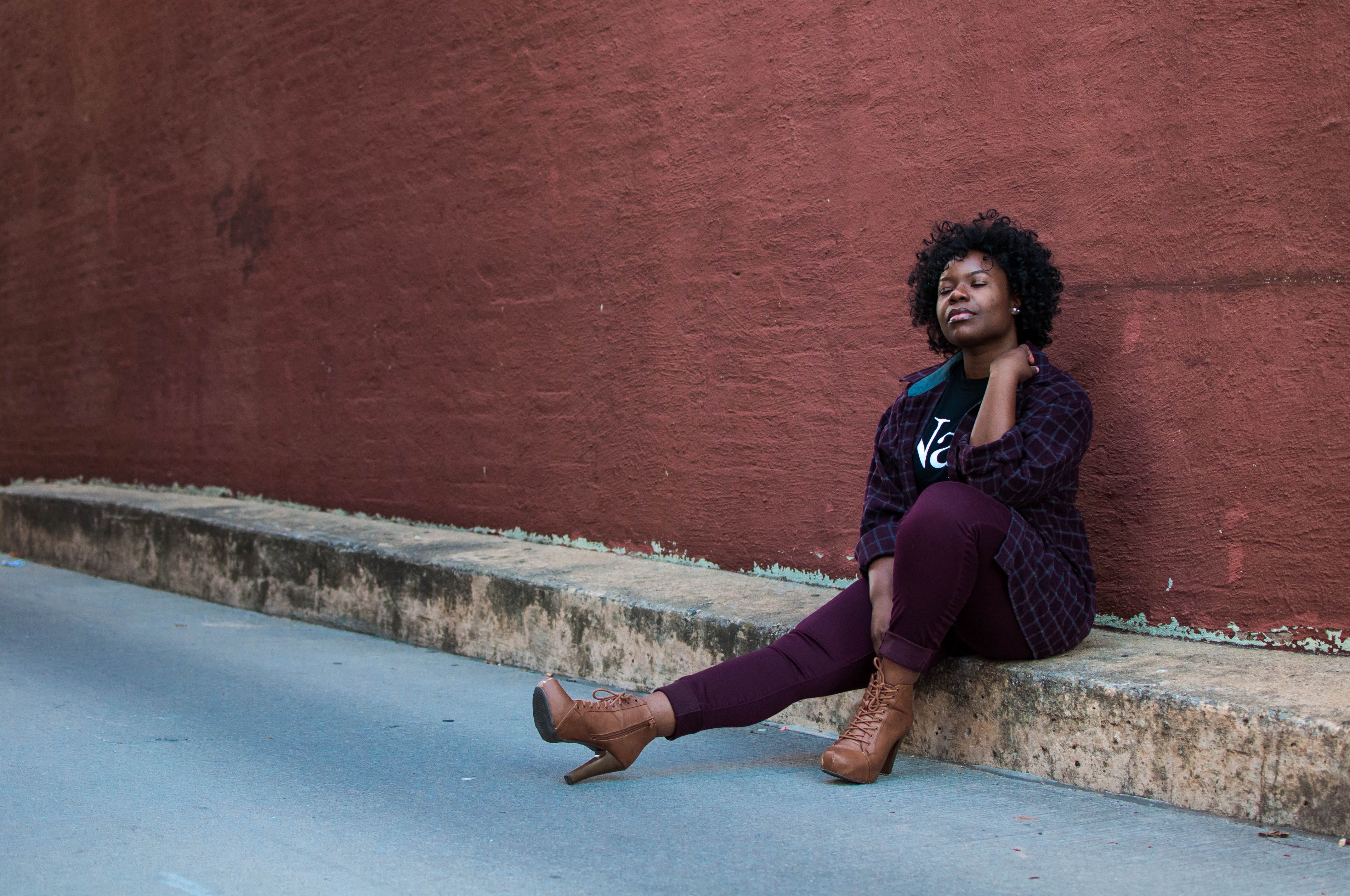 Woman with curly hair sitting by a wall HD Wallpaper