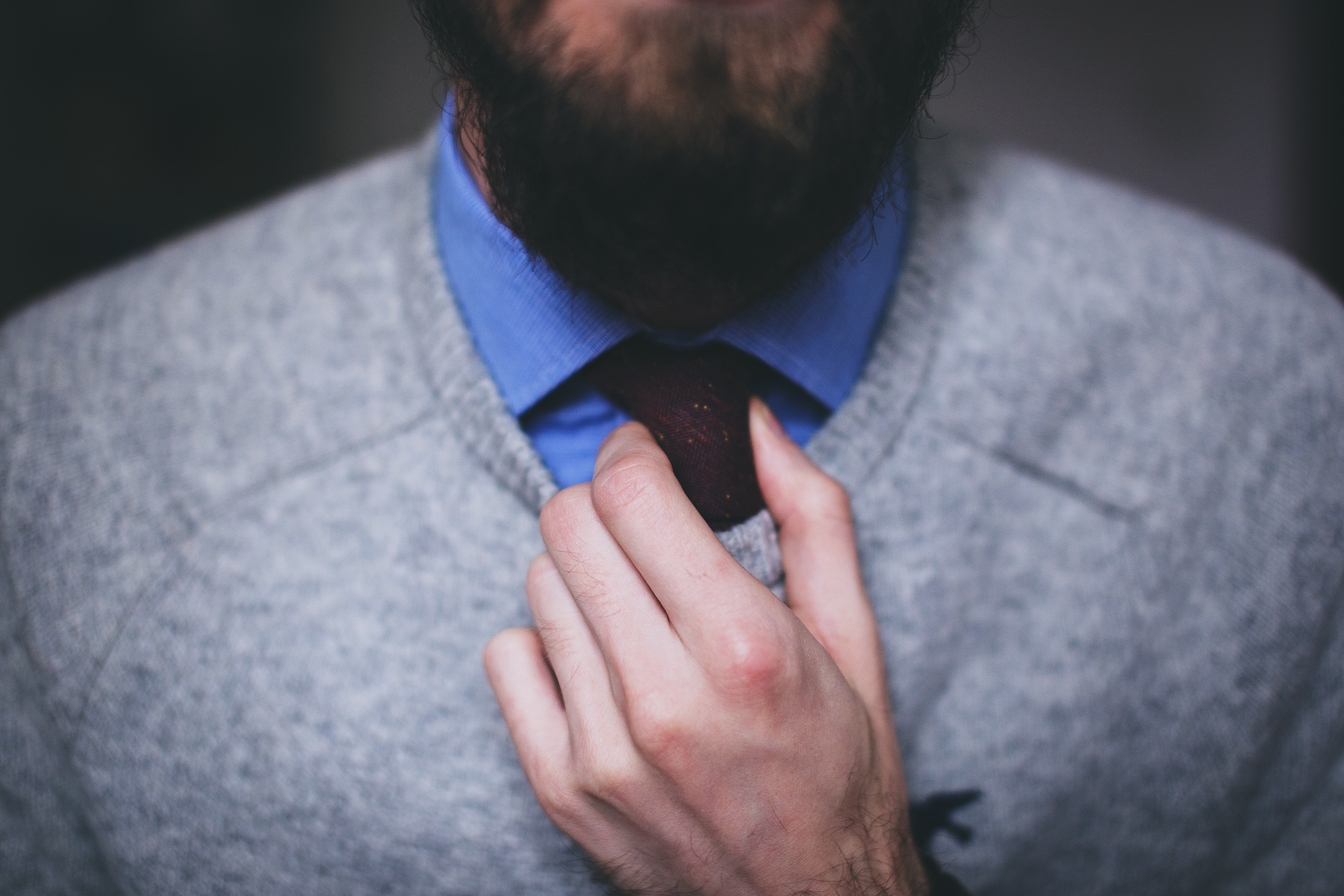 Man adjusting his tie and sweater HD Wallpaper