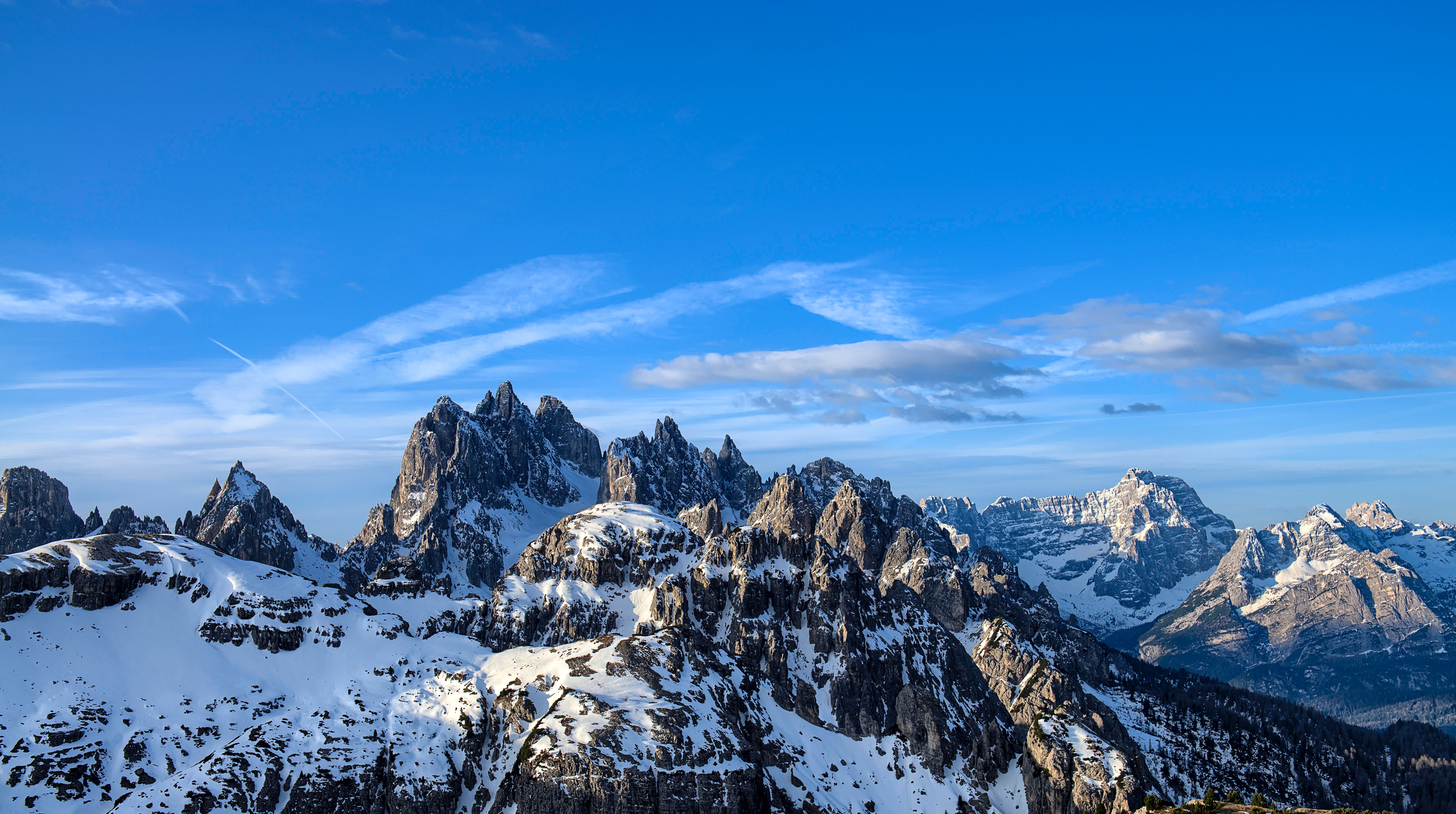 Snow-covered mountain range under a blue sky HD Wallpaper