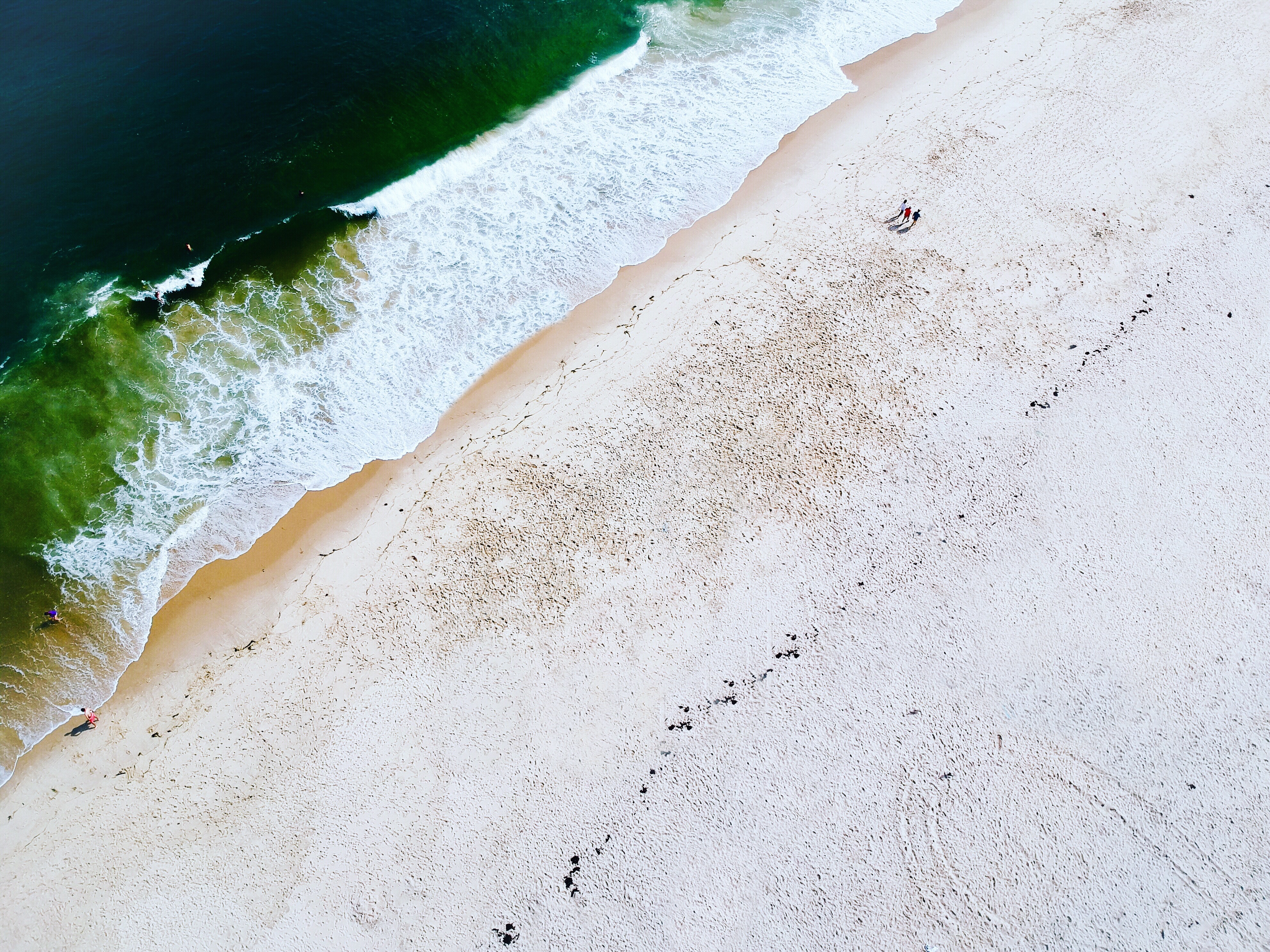 Aerial view of a beach with people walking HD Wallpaper