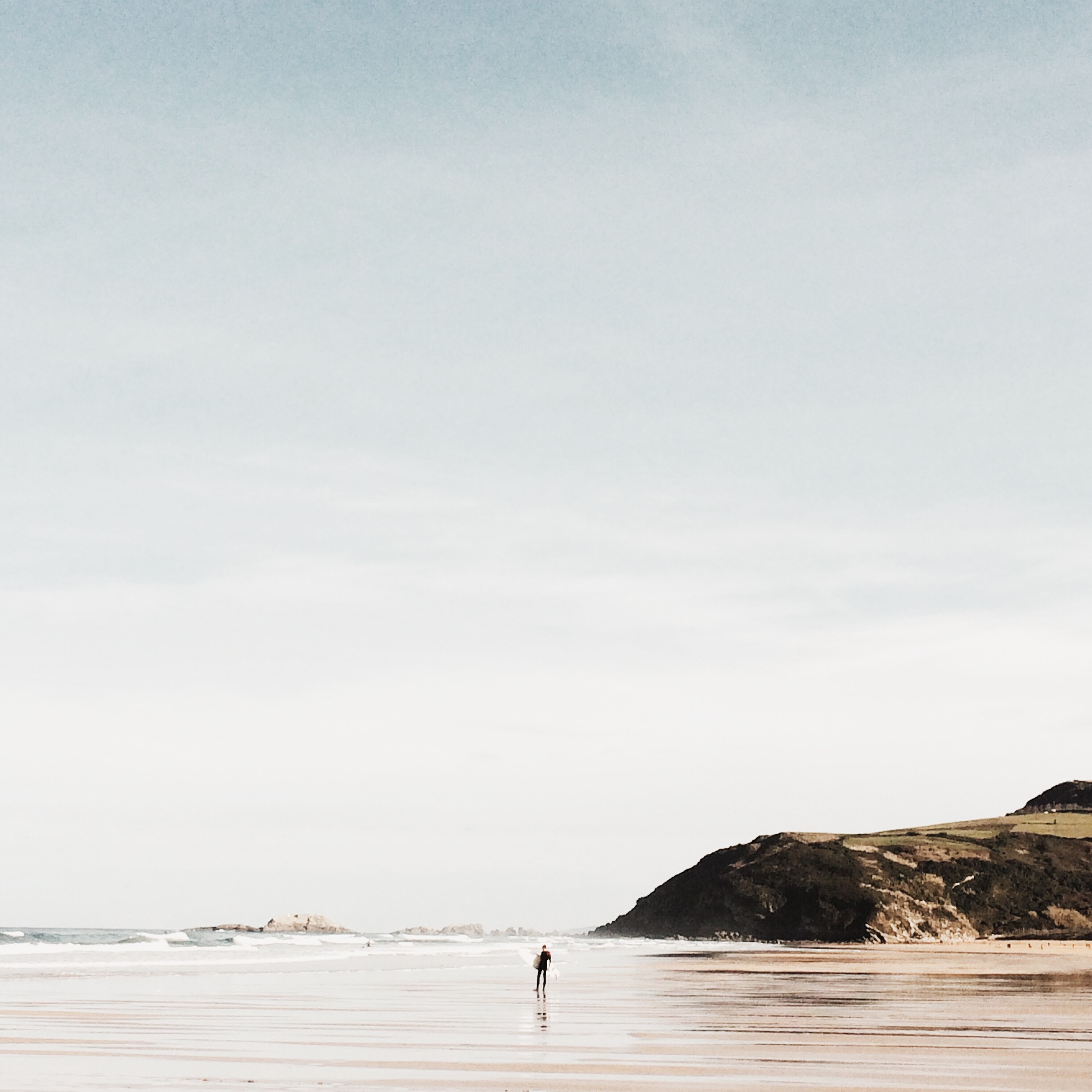 Man standing on a beach with a mountain in the background HD Wallpaper
