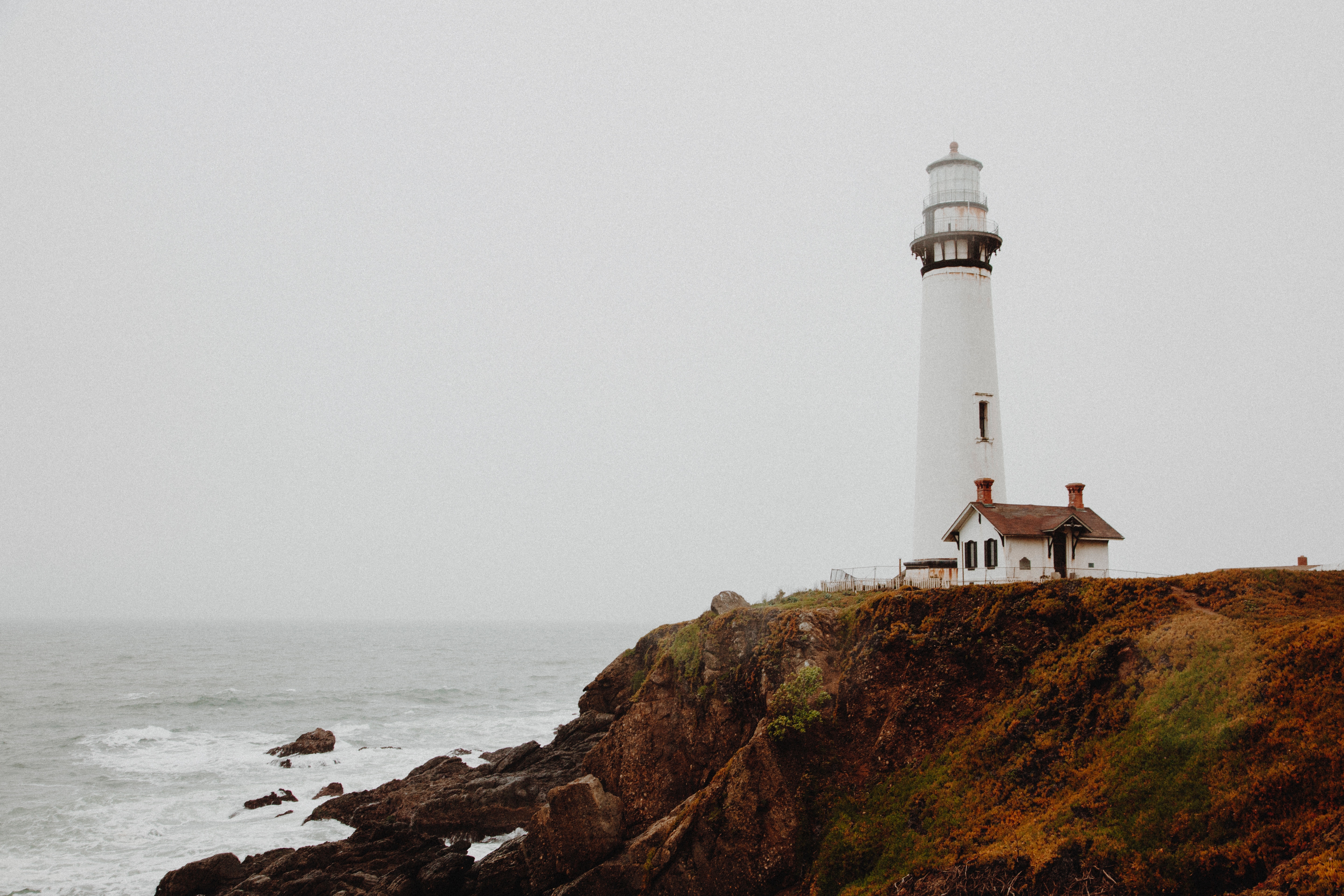 White lighthouse on a cliff overlooking the ocean HD Wallpaper