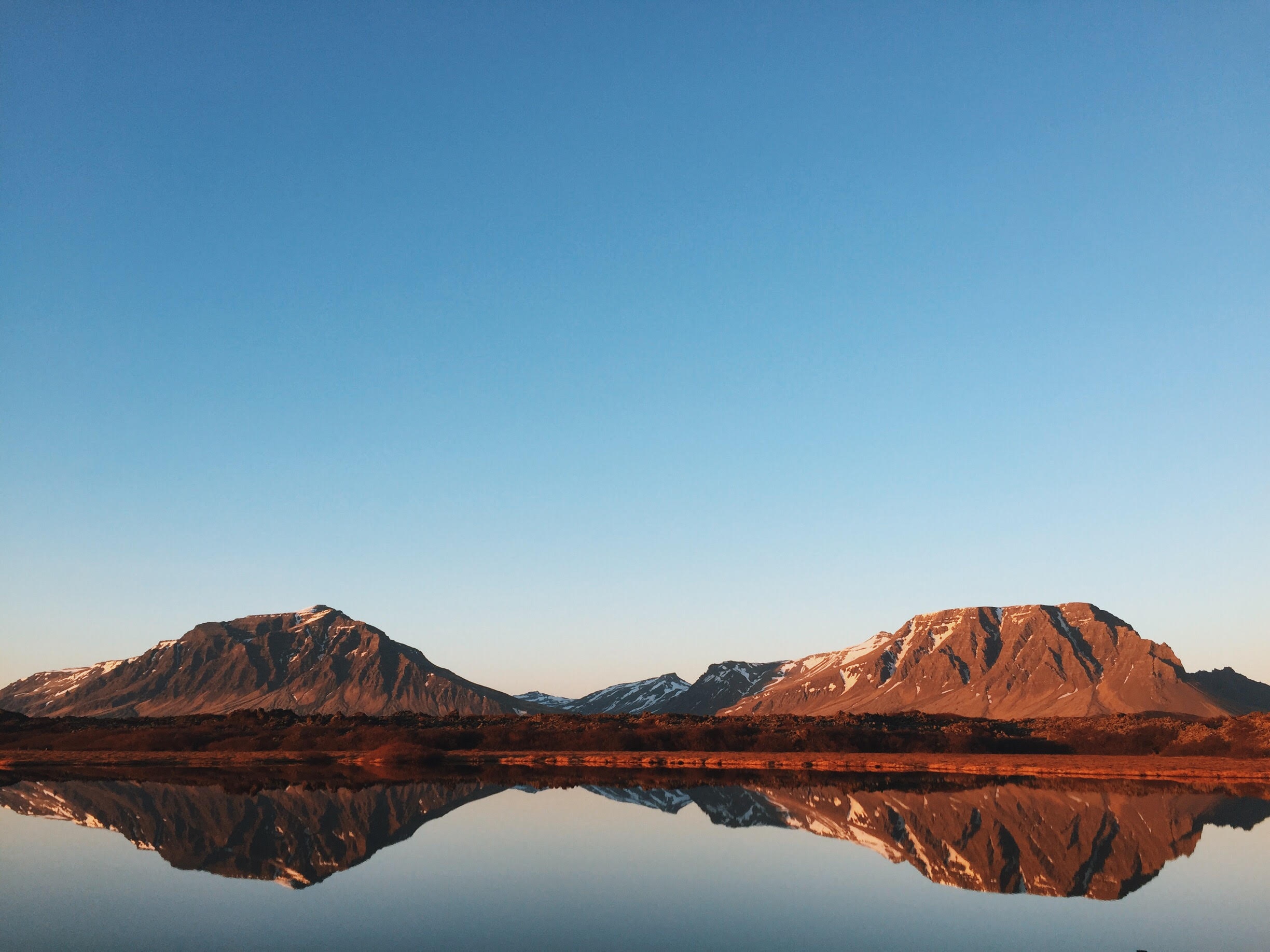 Mountain range reflected in a lake at sunrise or sunset HD Wallpaper