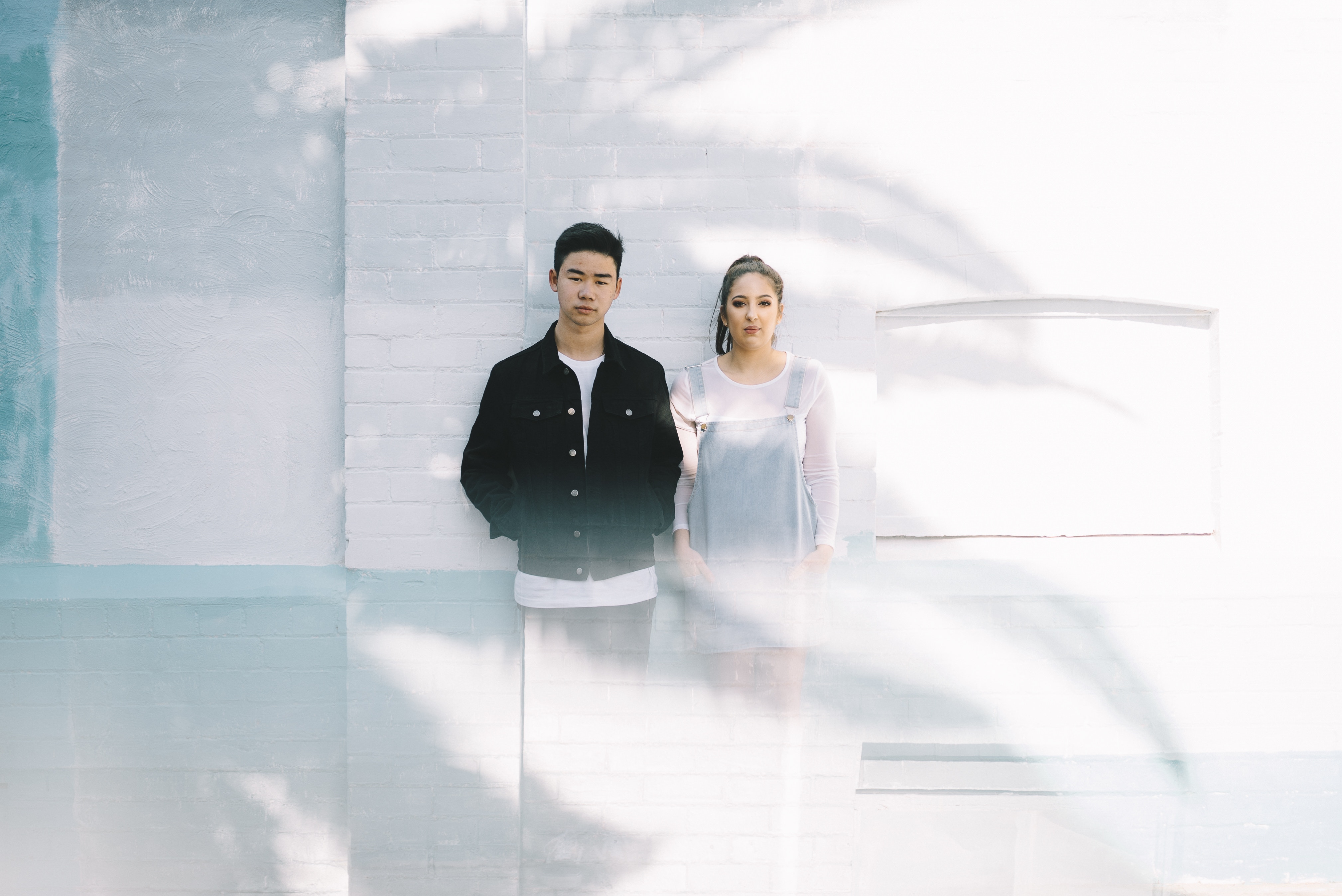 Asian couple posing against a white brick wall HD Wallpaper