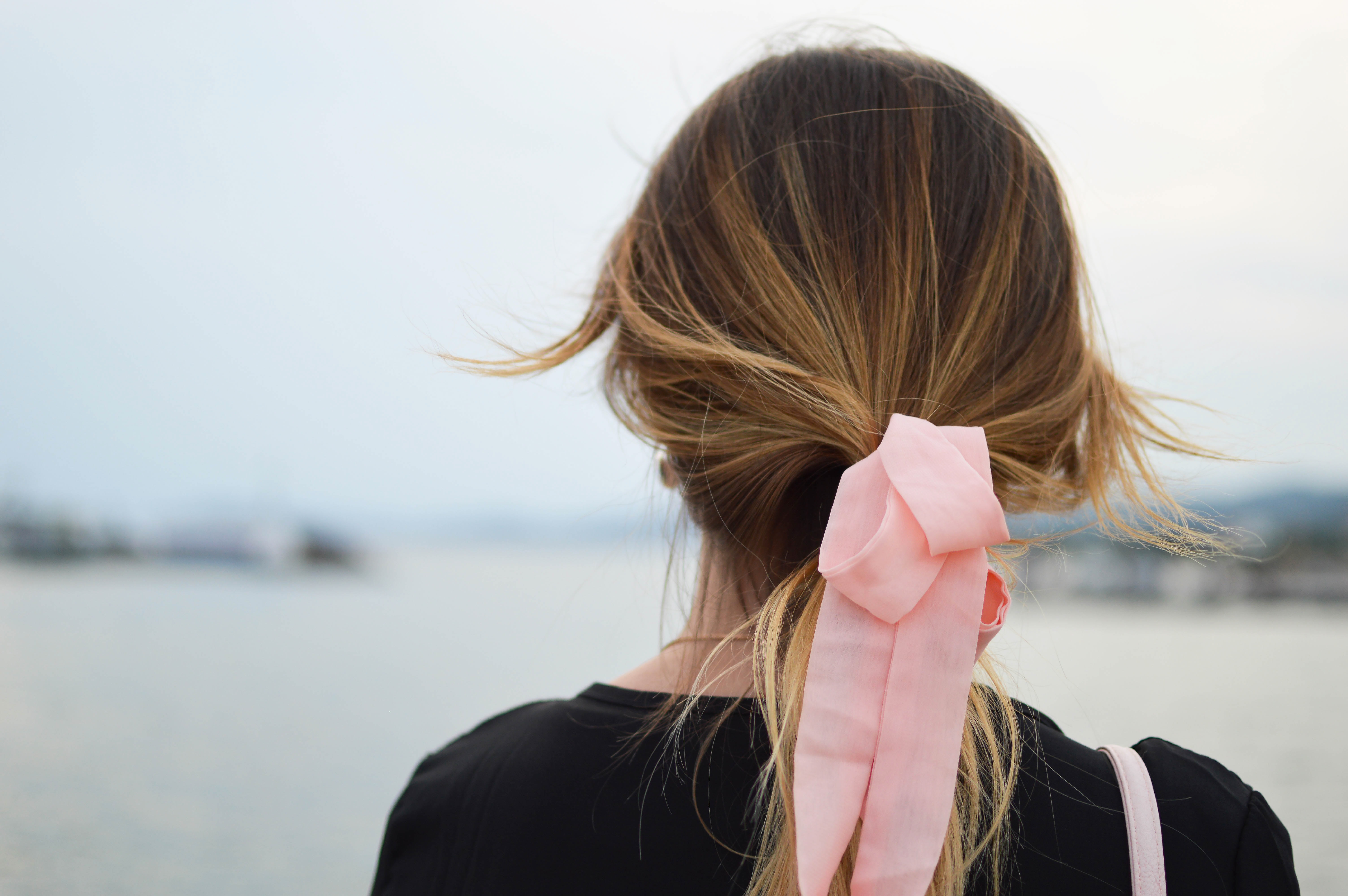 Woman with pink bow in her hair by the sea HD Wallpaper