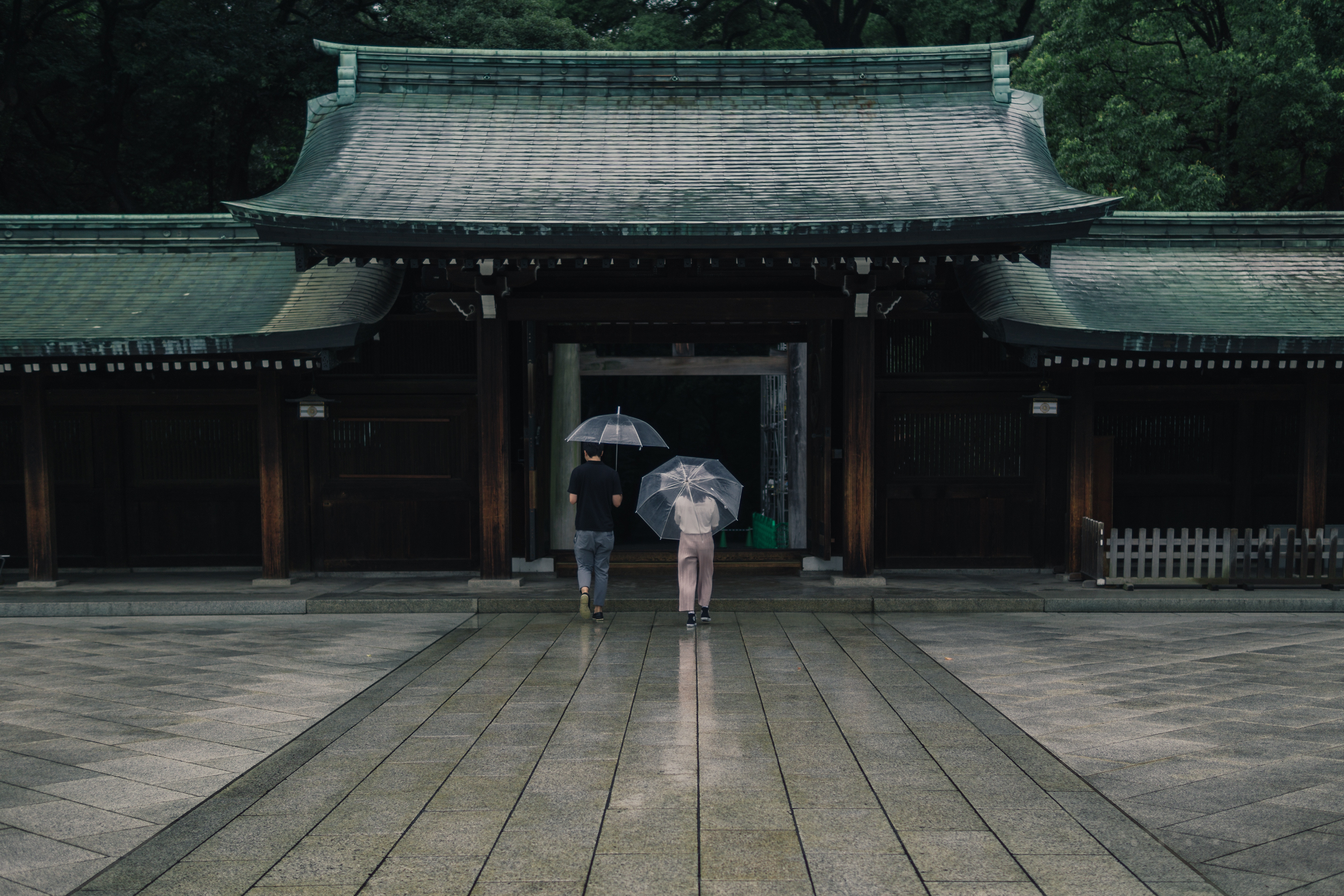 Two people with umbrellas walk towards Meiji Jingu shrine in Tokyo HD Wallpaper