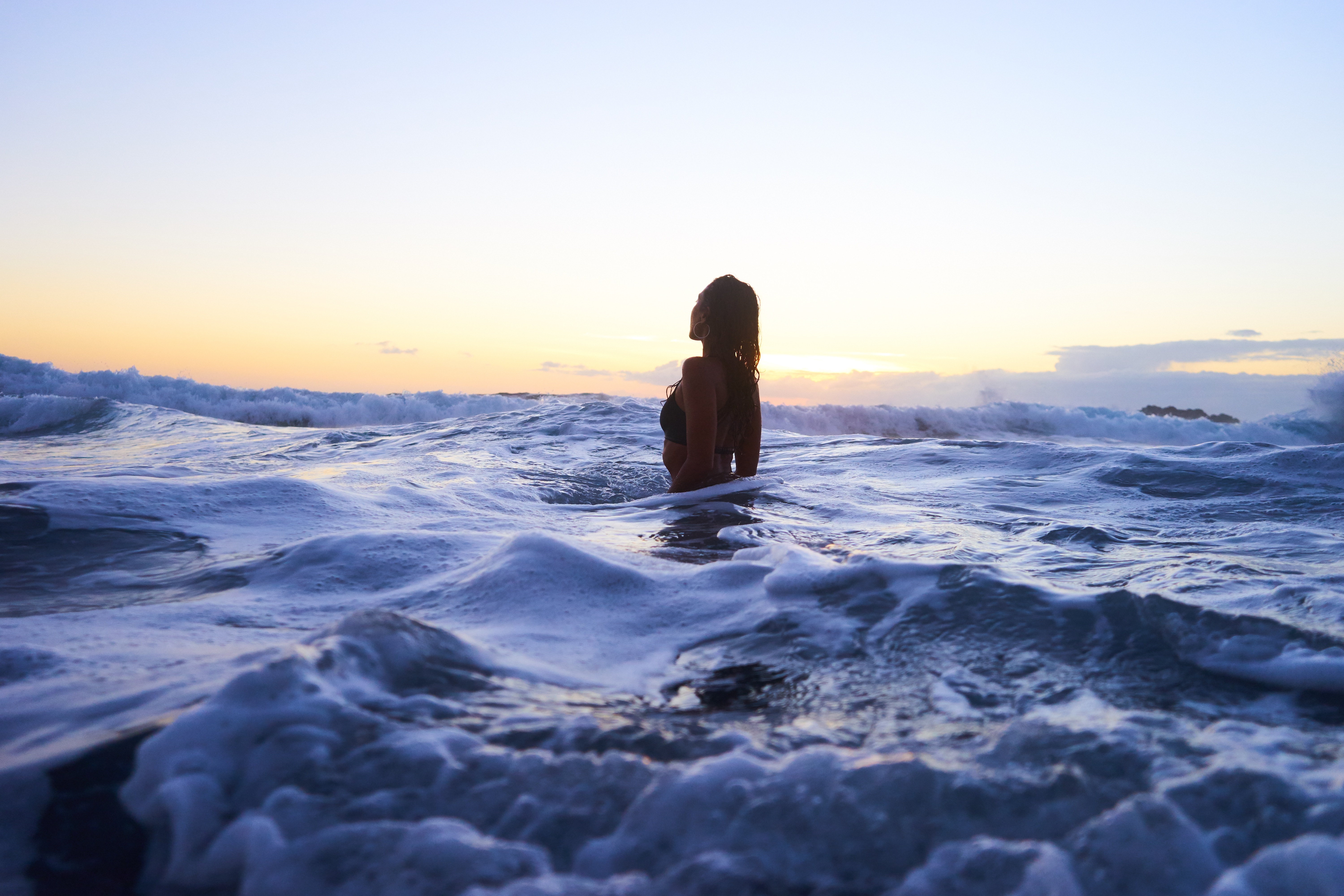 Woman wading in ocean waves at sunset HD Wallpaper