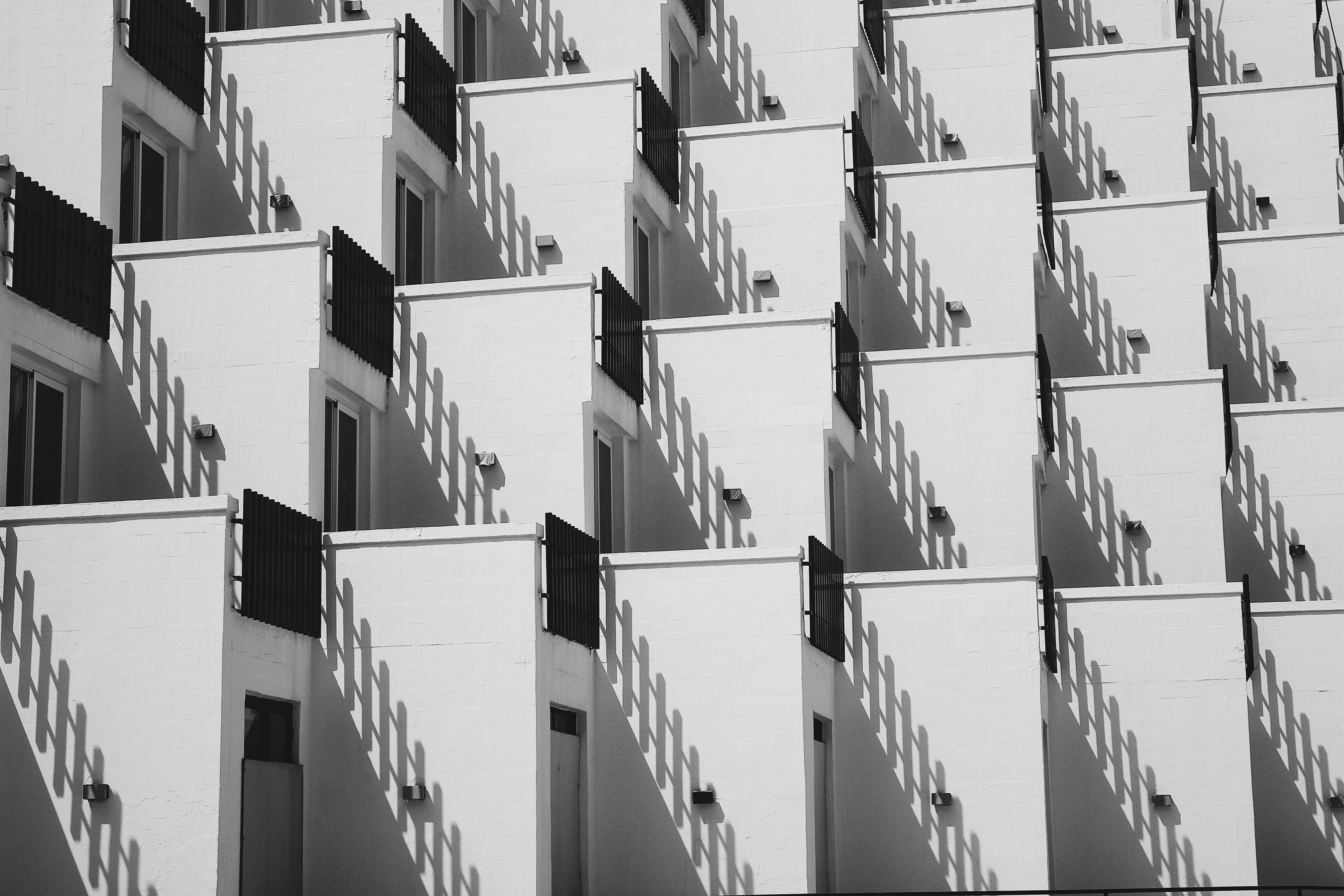 Geometric pattern of white balconies with black railings and shadows HD Wallpaper