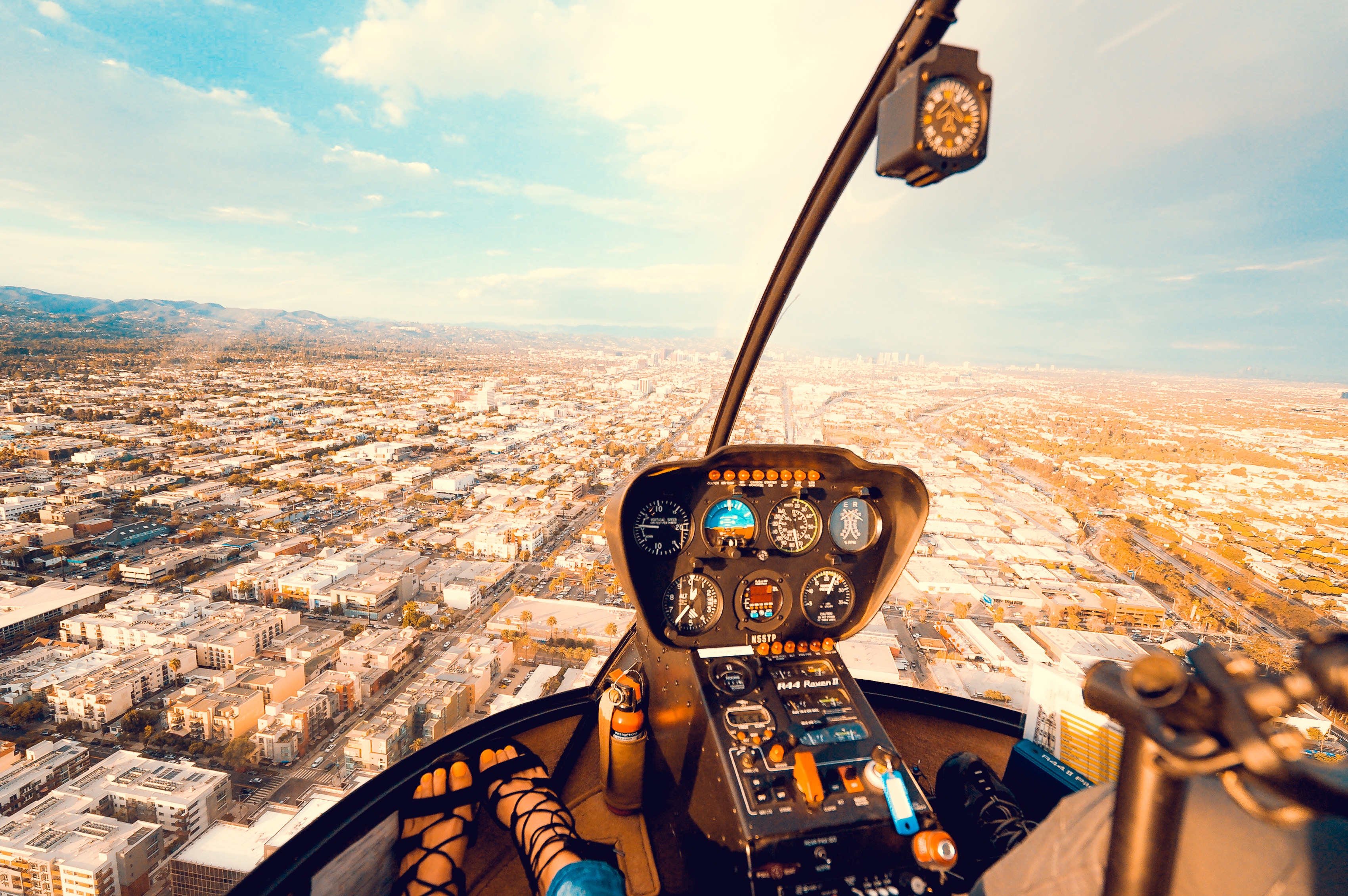 Helicopter cockpit view over a sprawling cityscape HD Wallpaper