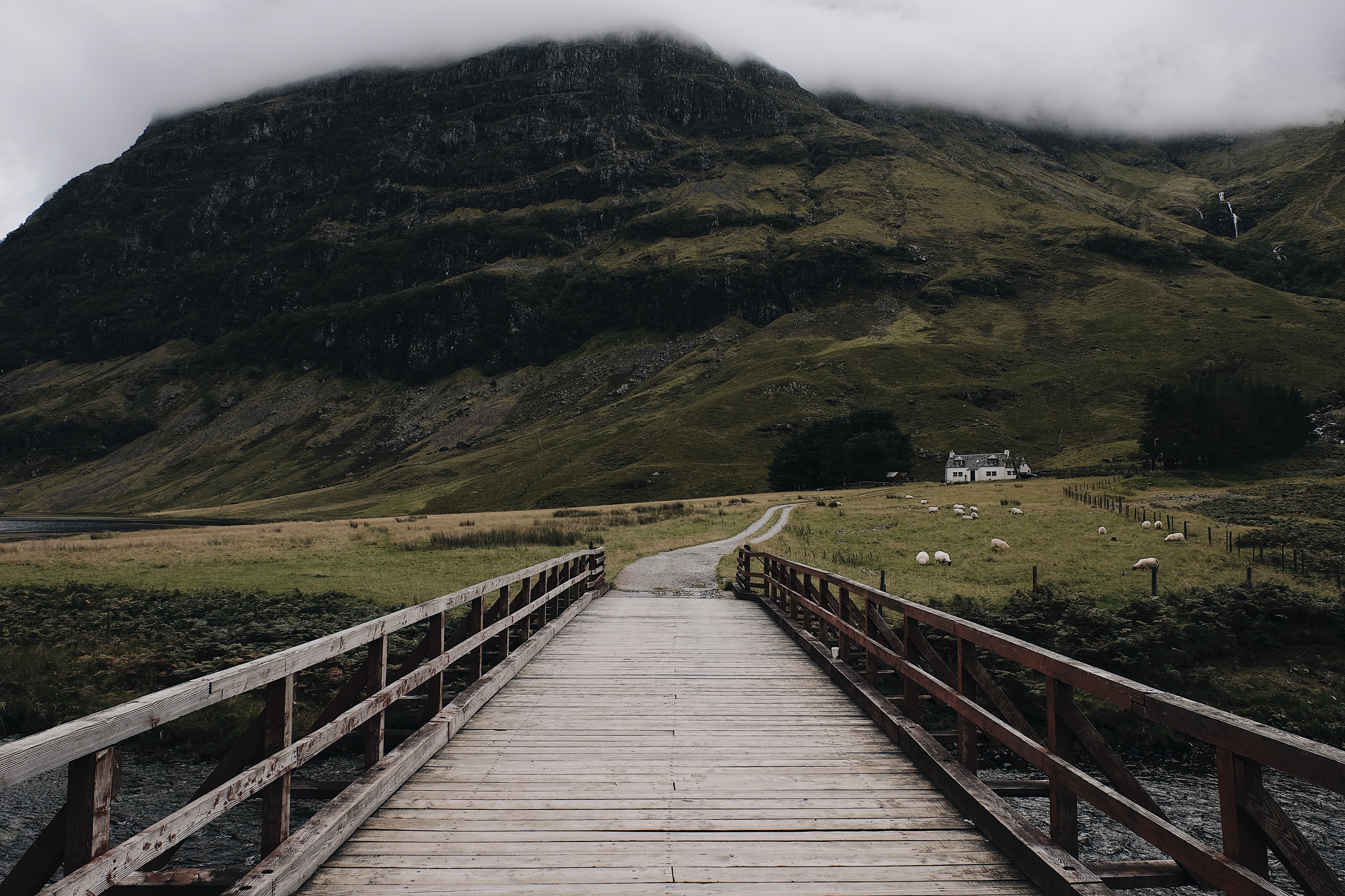 Wooden bridge leading to a farmhouse in a foggy mountain landscape HD Wallpaper