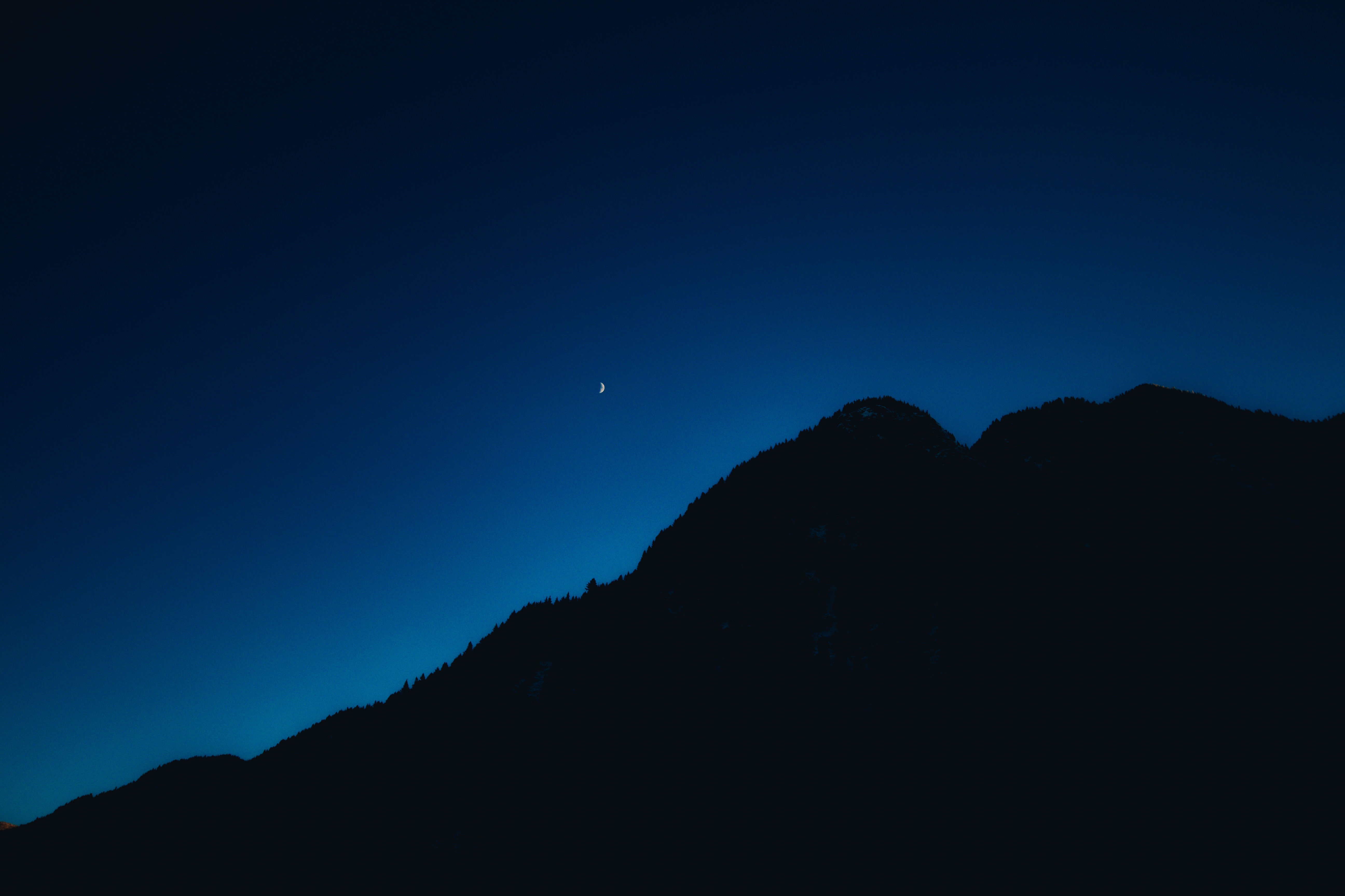 Crescent moon over silhouetted mountain range at night HD Wallpaper