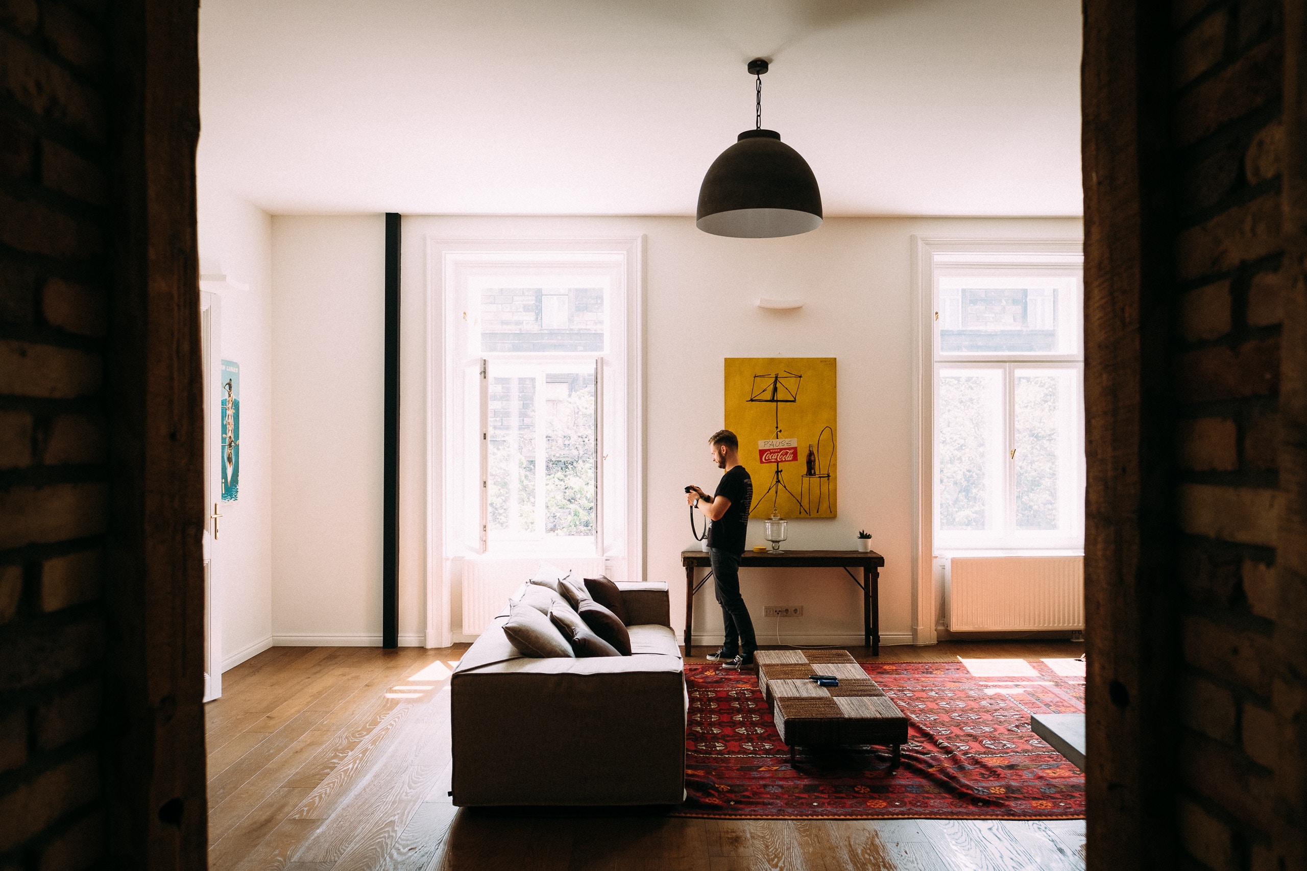 Man in a living room with a couch and artwork HD Wallpaper