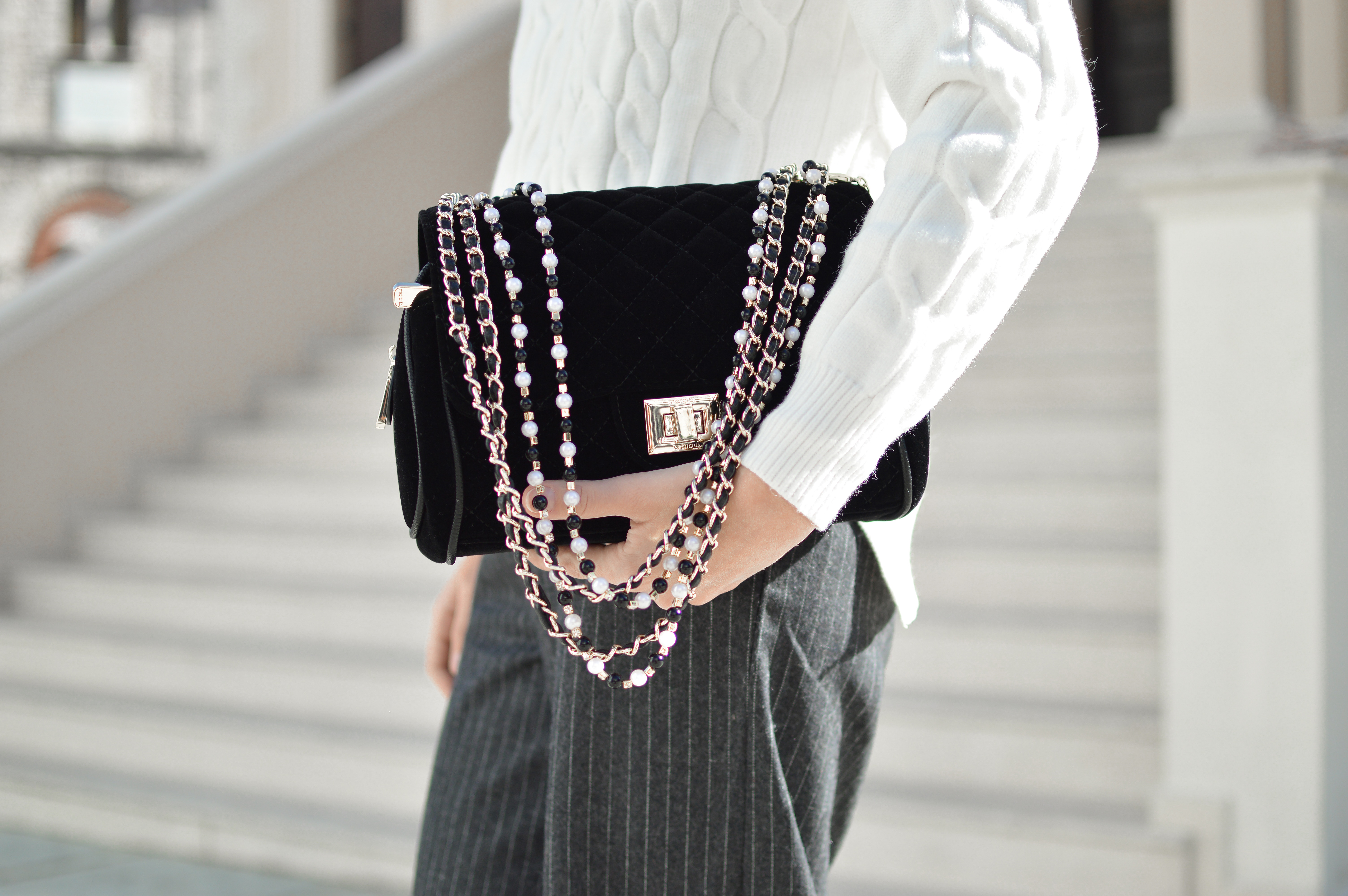 Woman holding a black quilted velvet handbag with beaded chain HD Wallpaper
