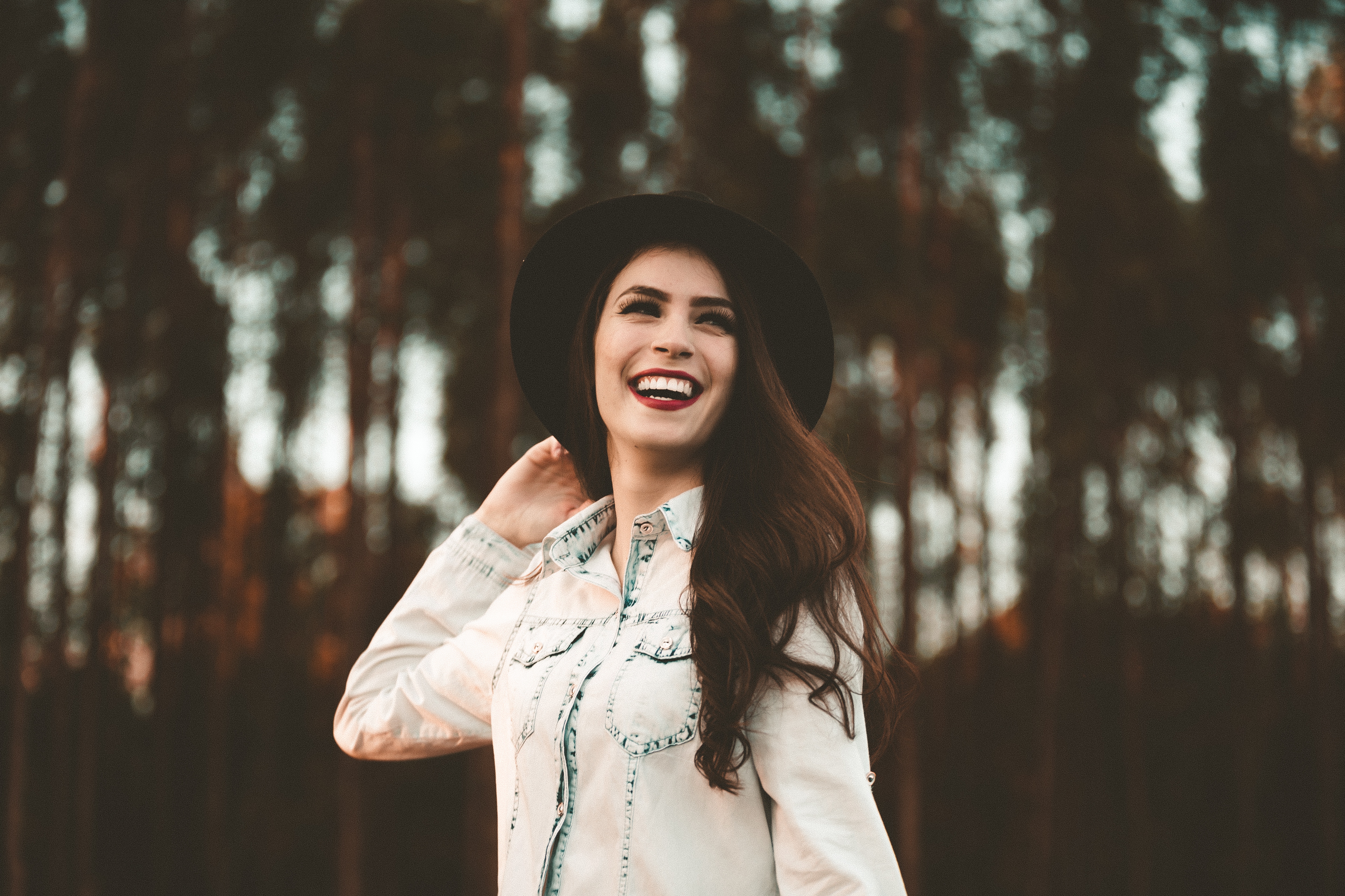 Woman in a hat smiling in a forest HD Wallpaper