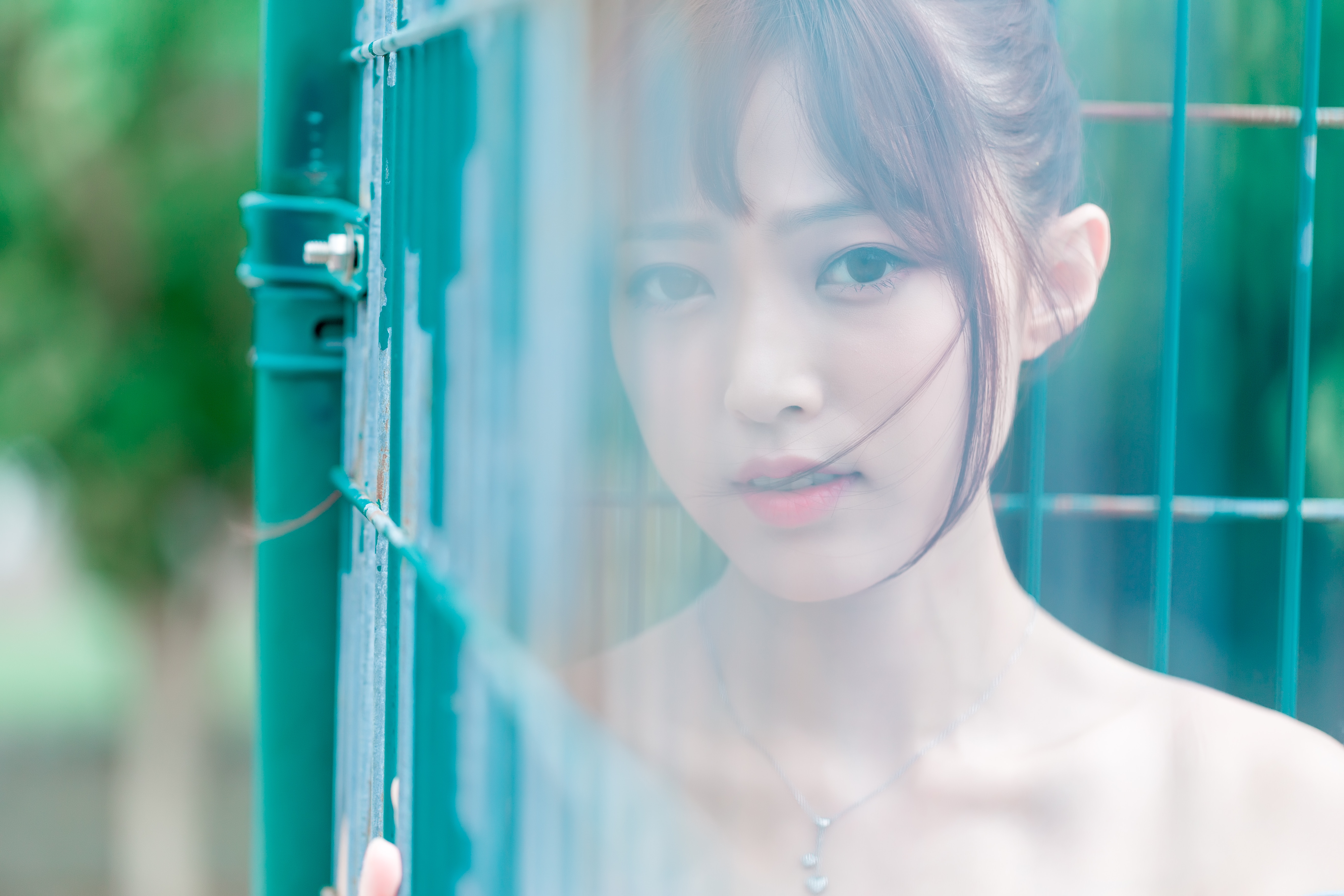 Young Asian woman behind a green fence HD Wallpaper