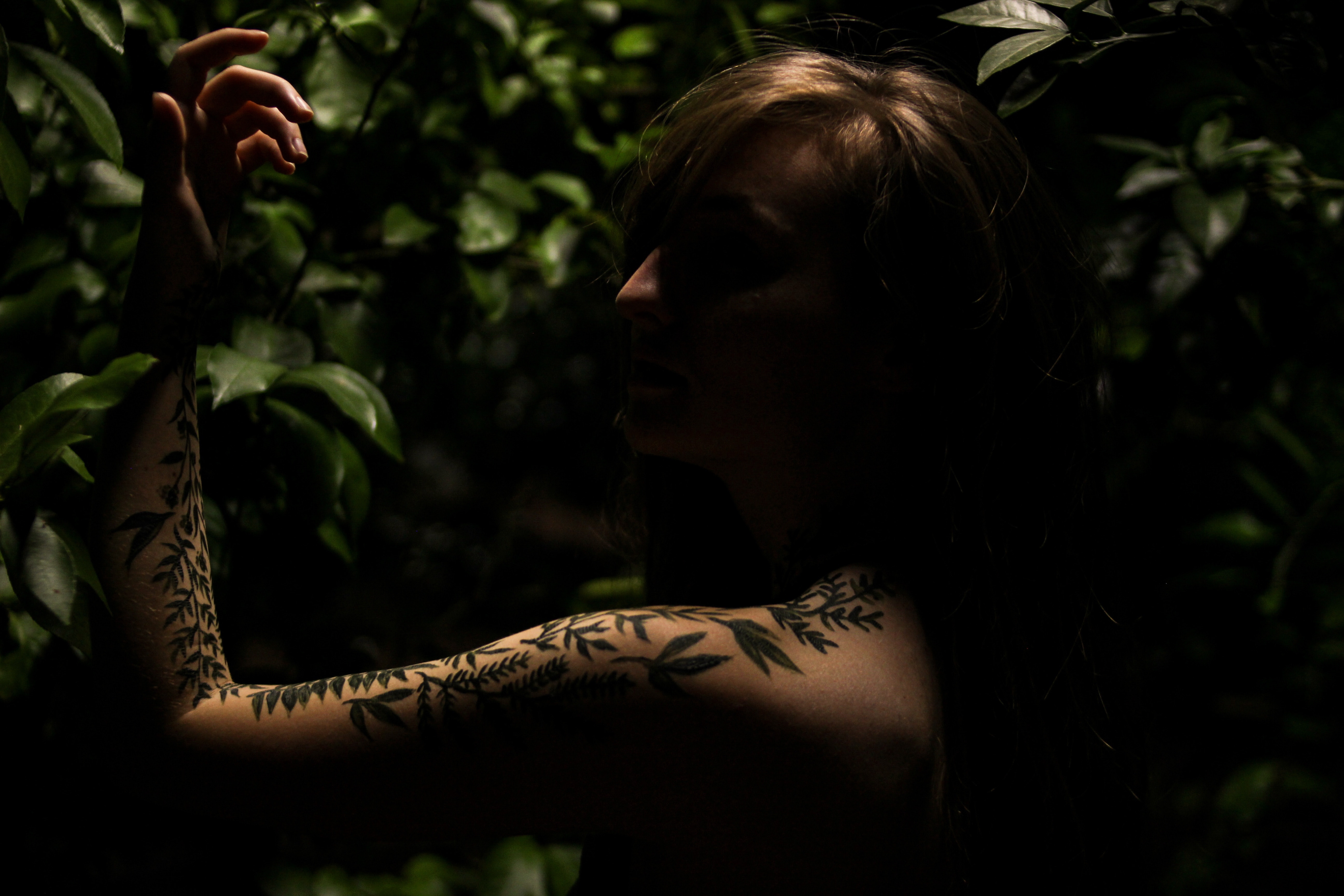 Woman with vine tattoo in dark nature setting HD Wallpaper