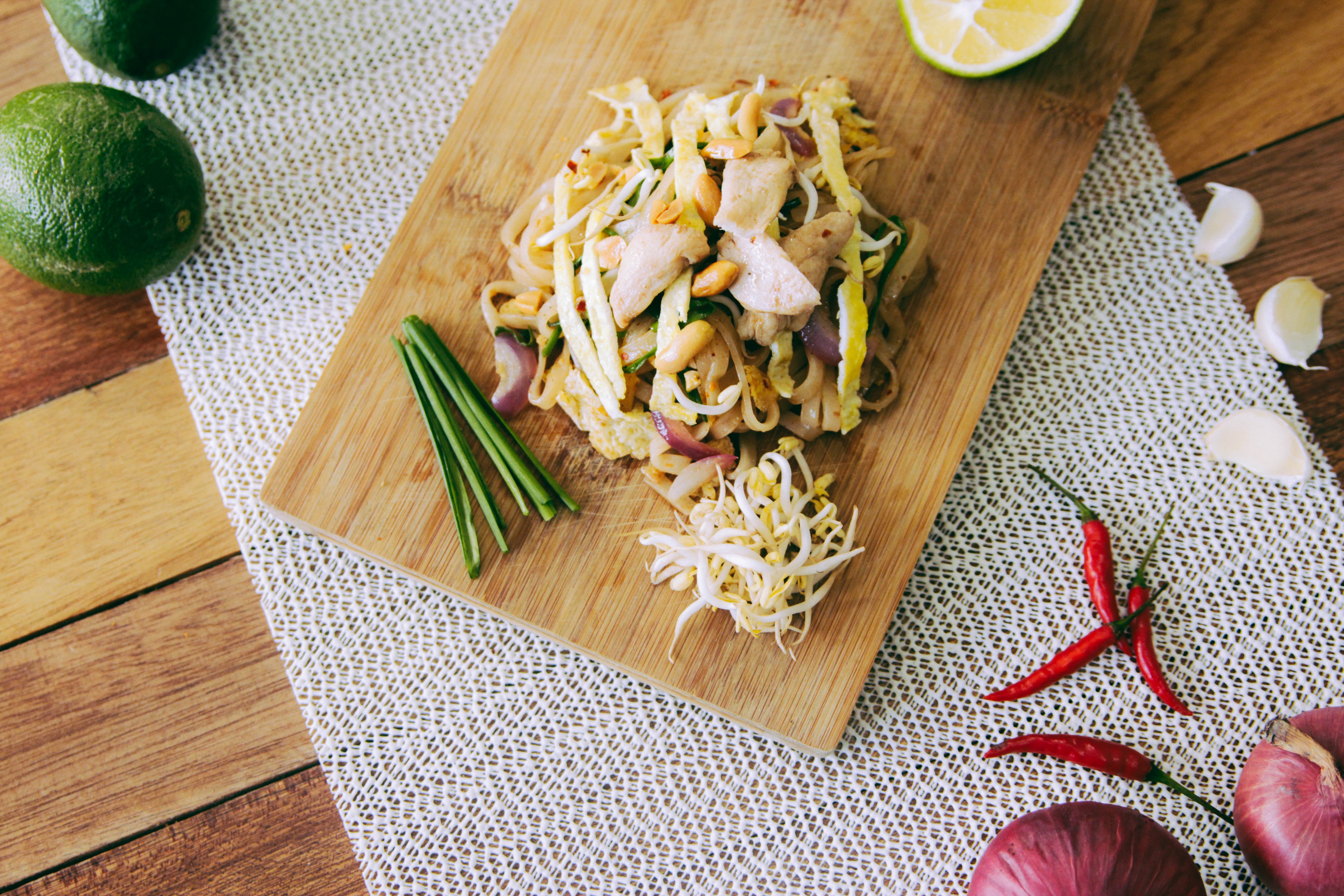 Pad Thai with chicken, lime, and chili on a wooden board HD Wallpaper