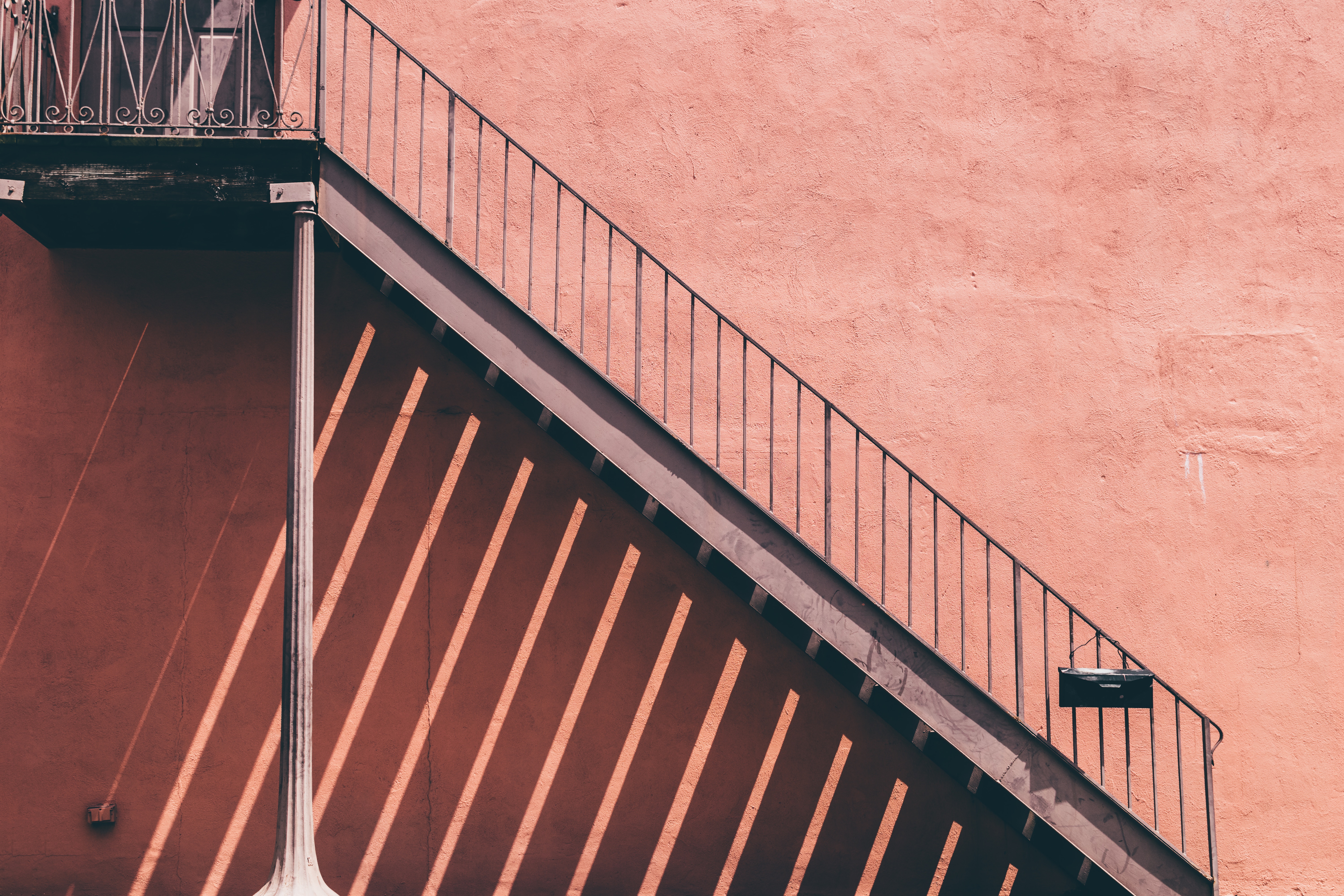 Pink wall with metal staircase and shadows HD Wallpaper