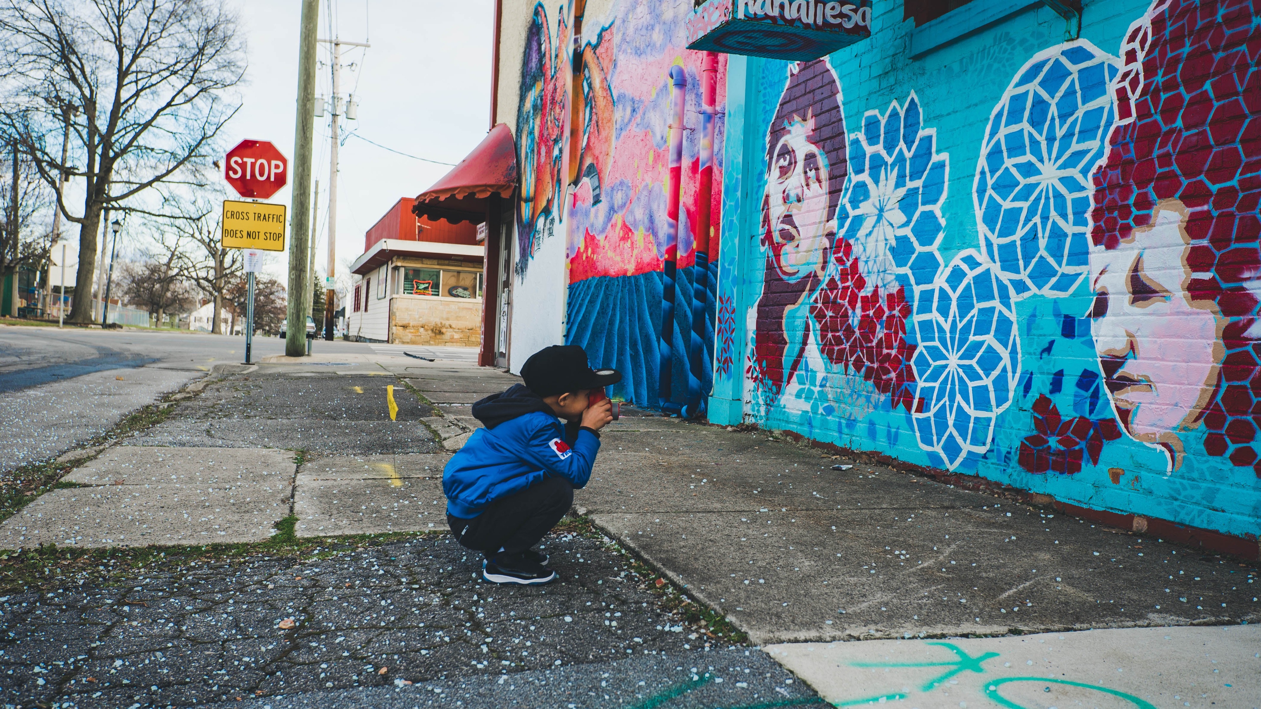 Child photographing a colorful mural on a city street HD Wallpaper