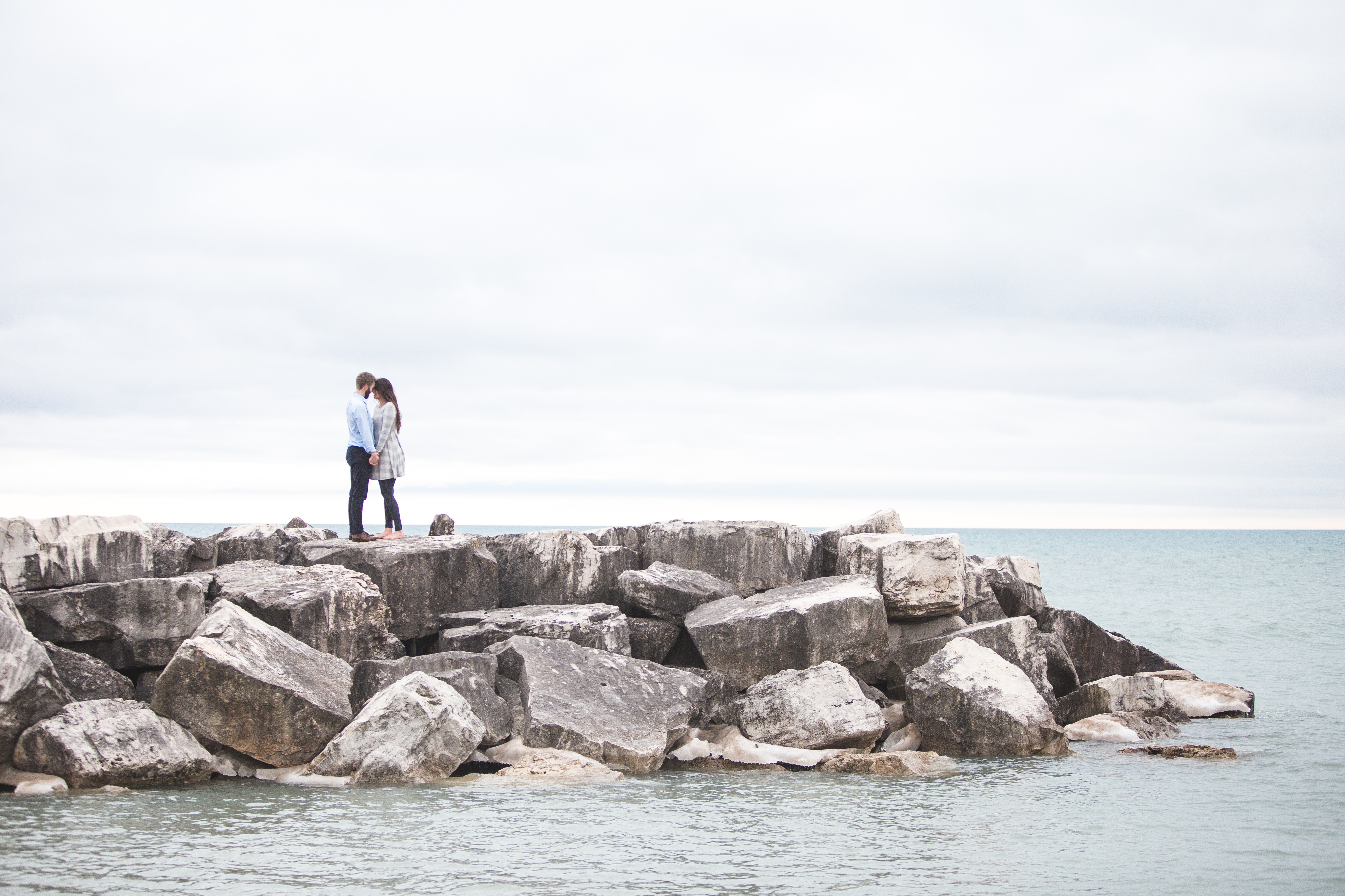 Couple embracing on rocks by the ocean HD Wallpaper