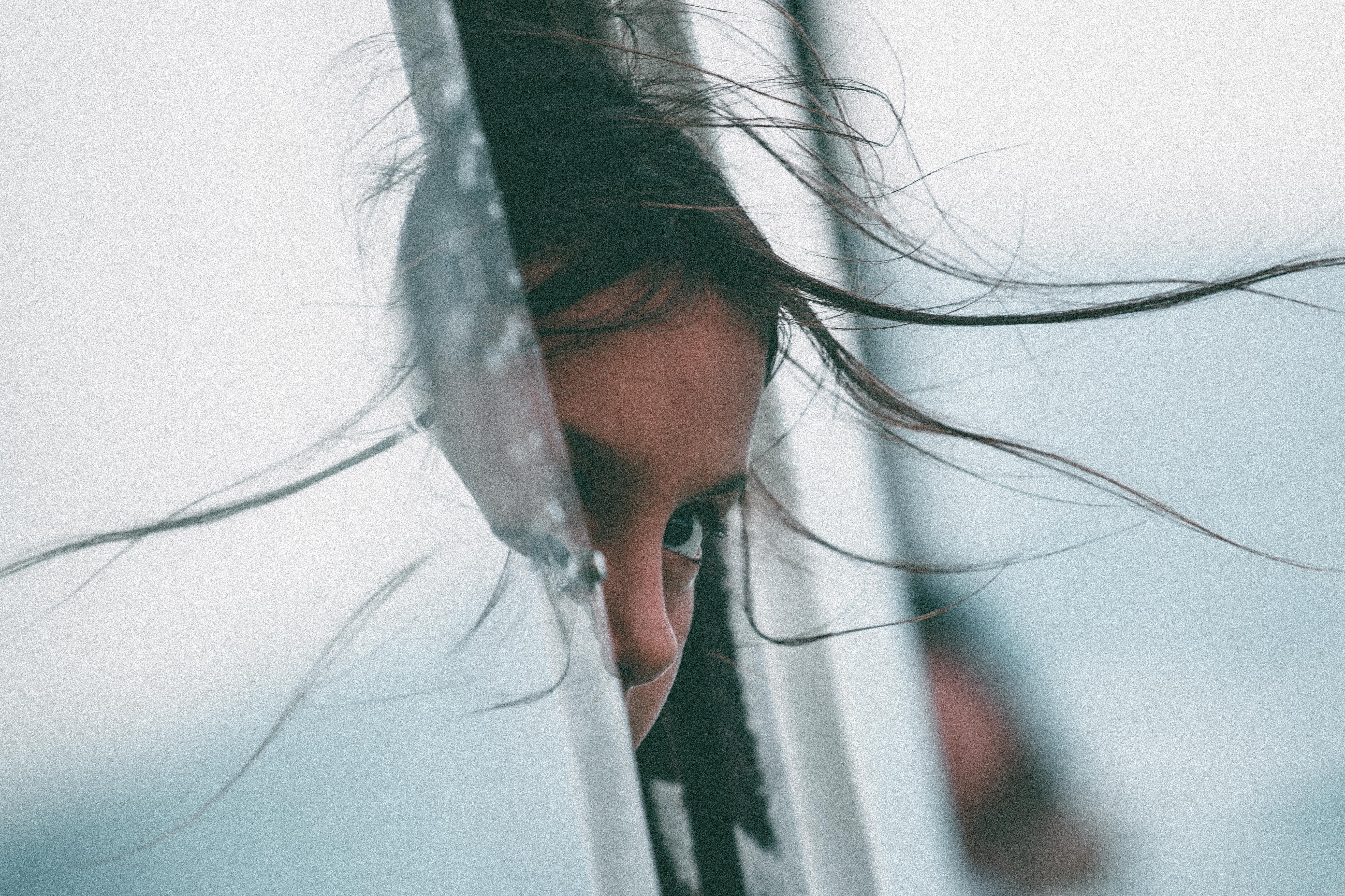Girl's face peeking through a window with windblown hair HD Wallpaper