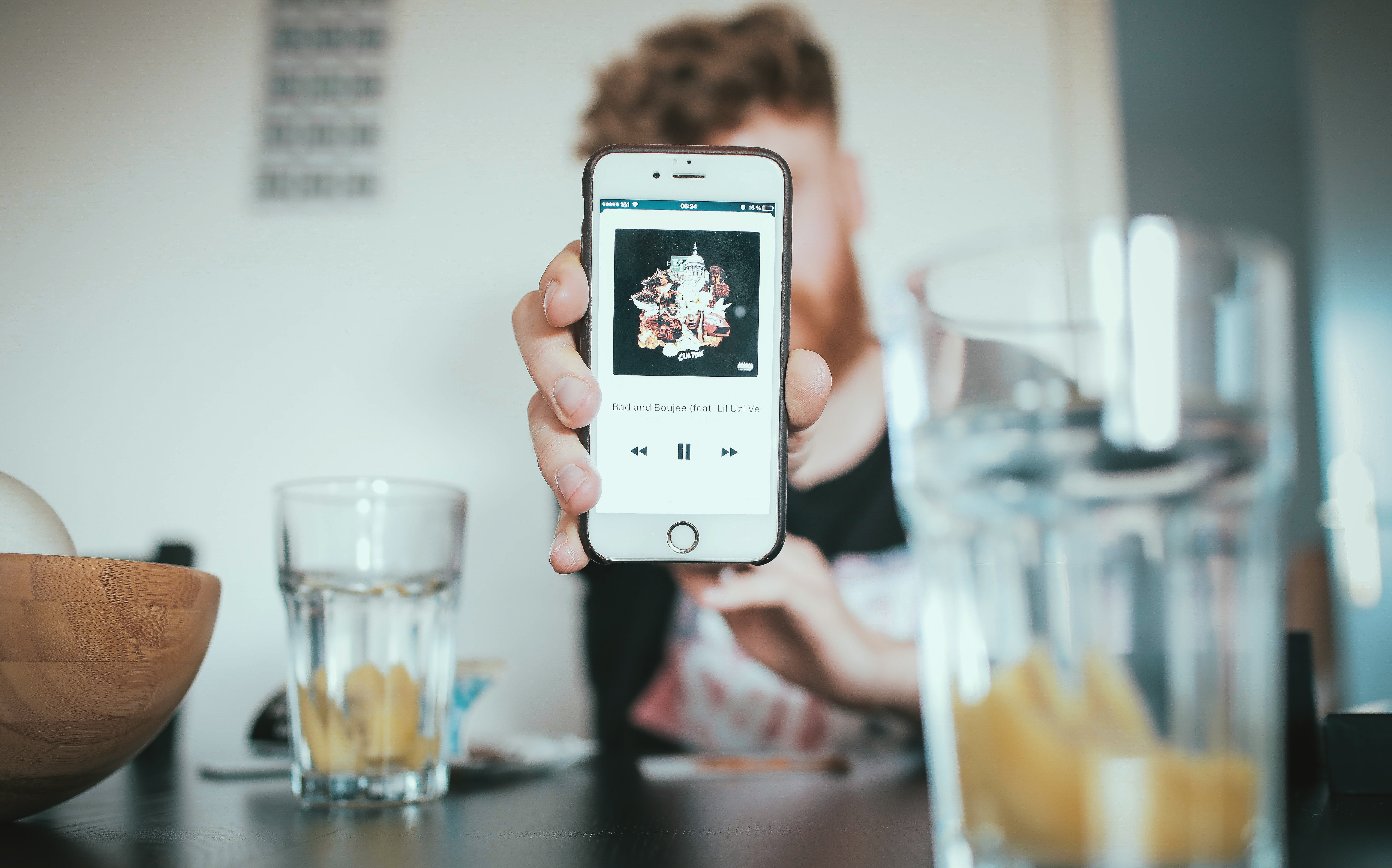 Man holding iPhone showing music app HD Wallpaper