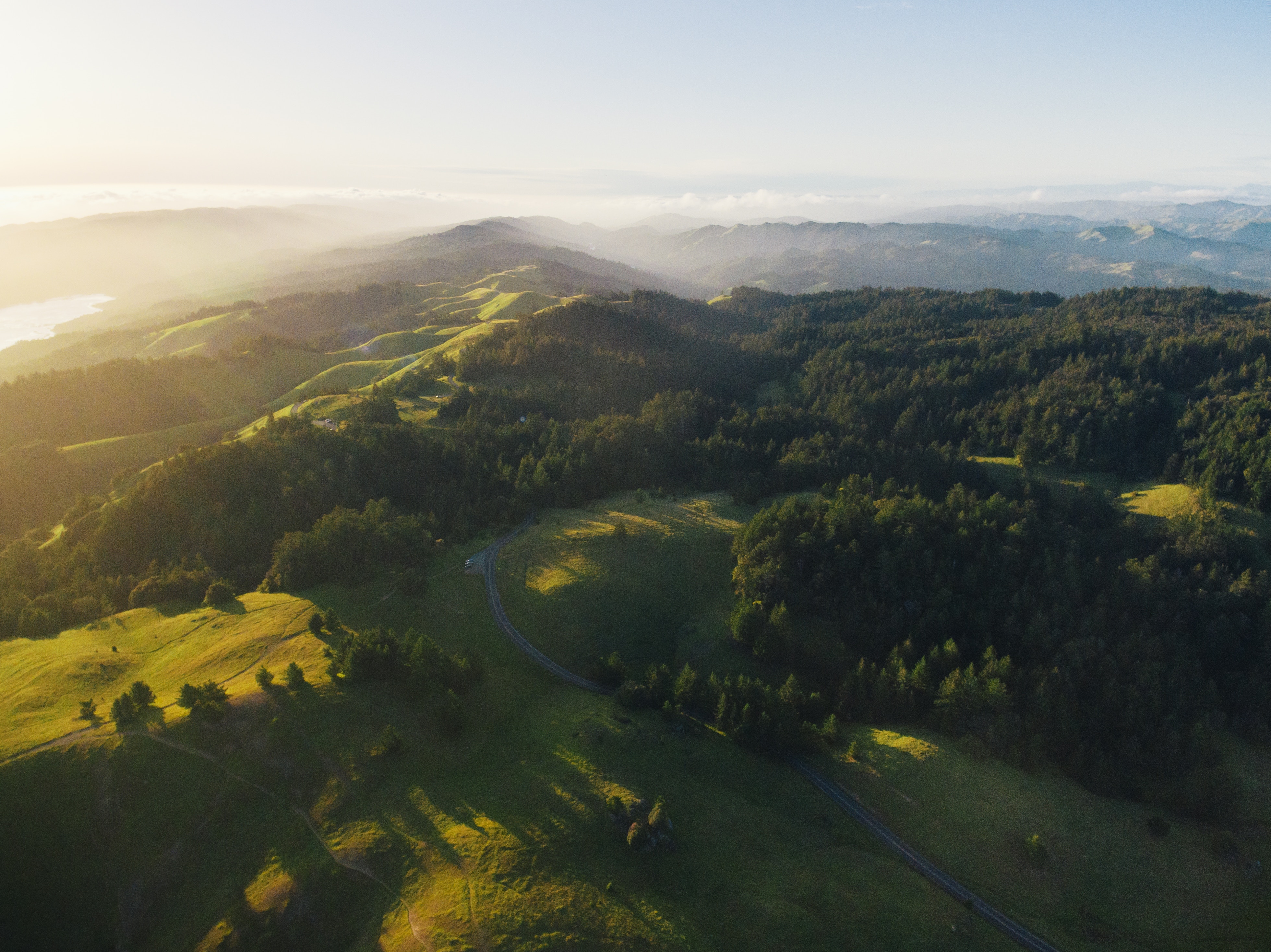 Aerial view of rolling hills and forests at sunrise HD Wallpaper
