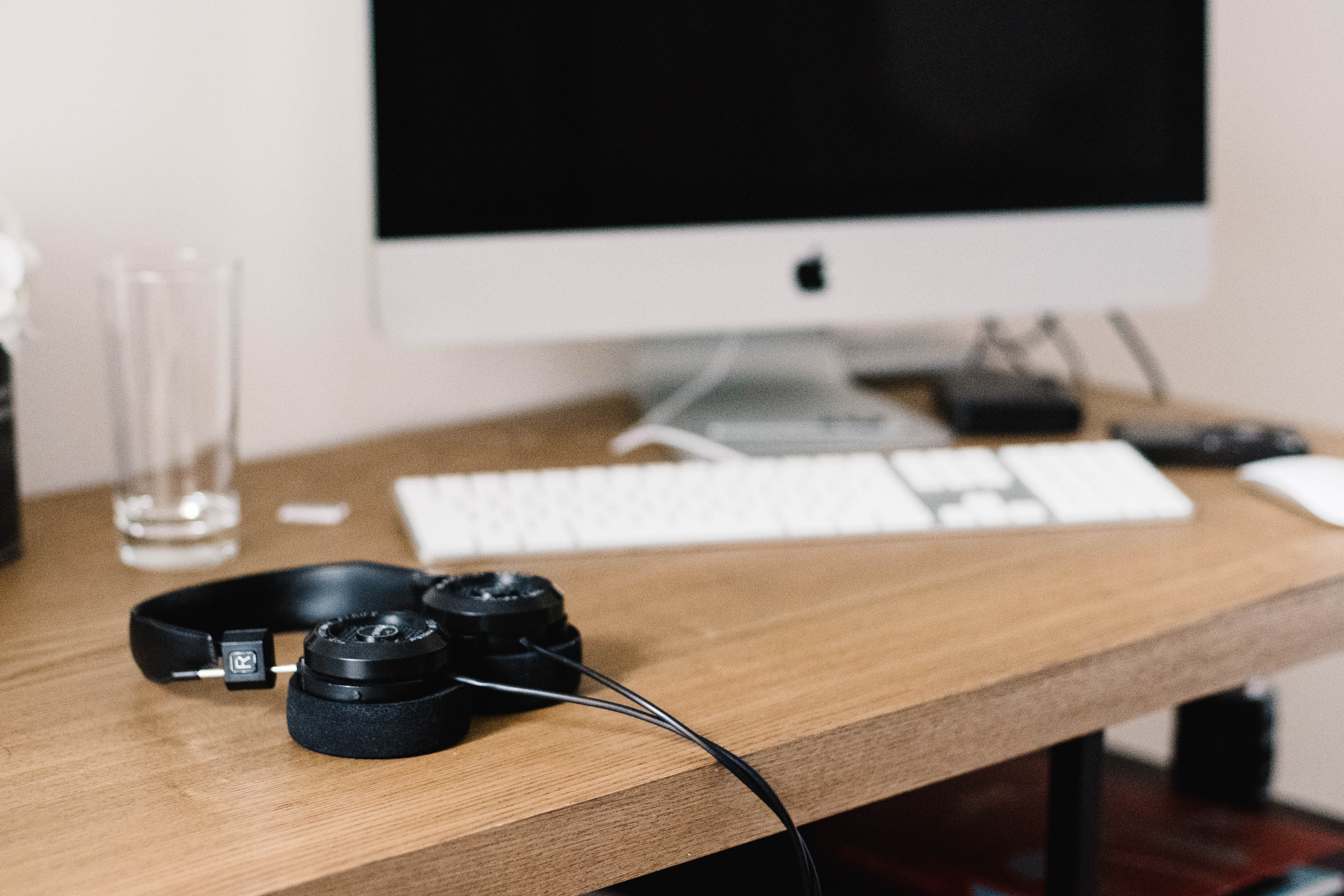 Apple iMac computer with headphones on a wooden desk HD Wallpaper