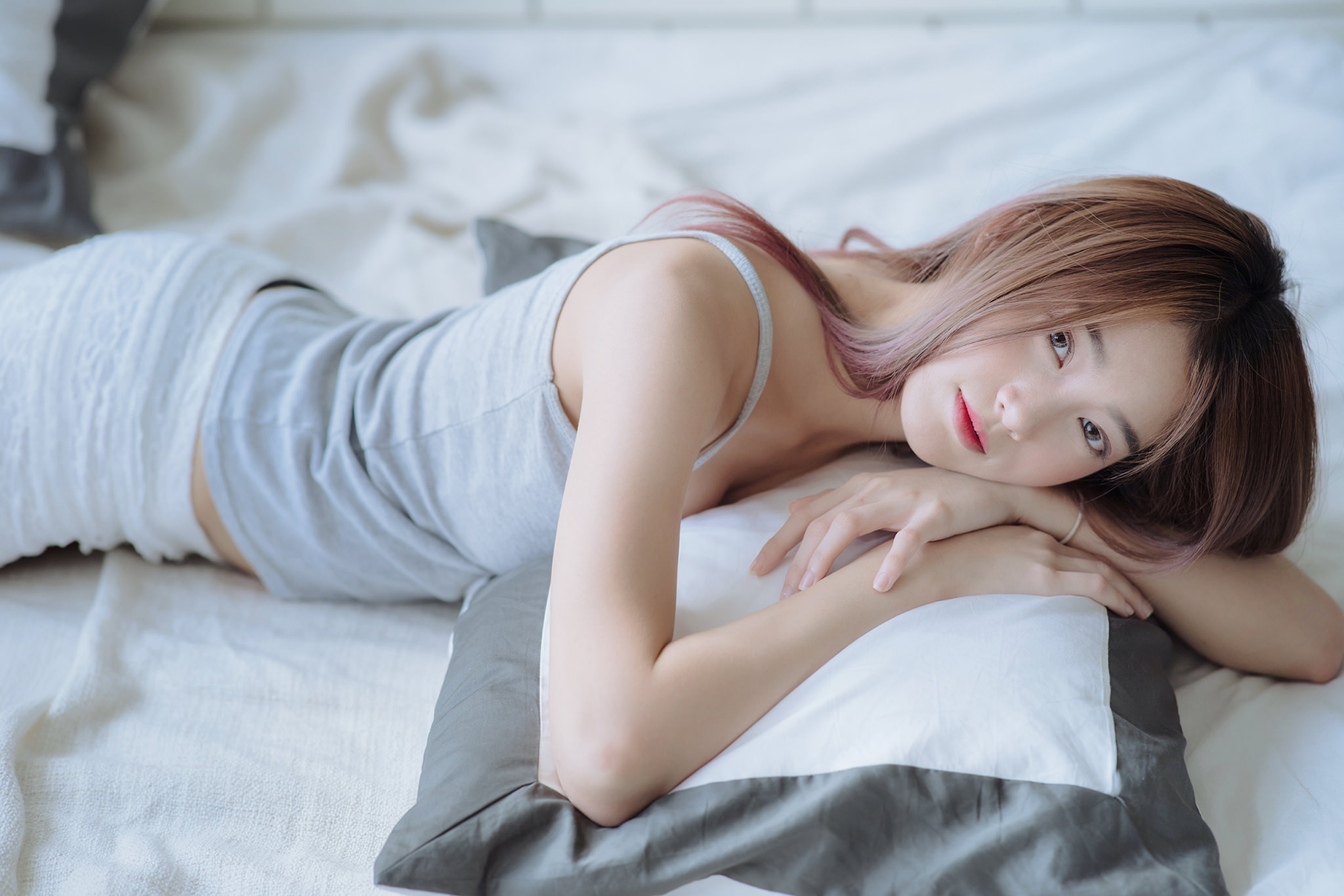Asian woman lying on a bed with pillows HD Wallpaper
