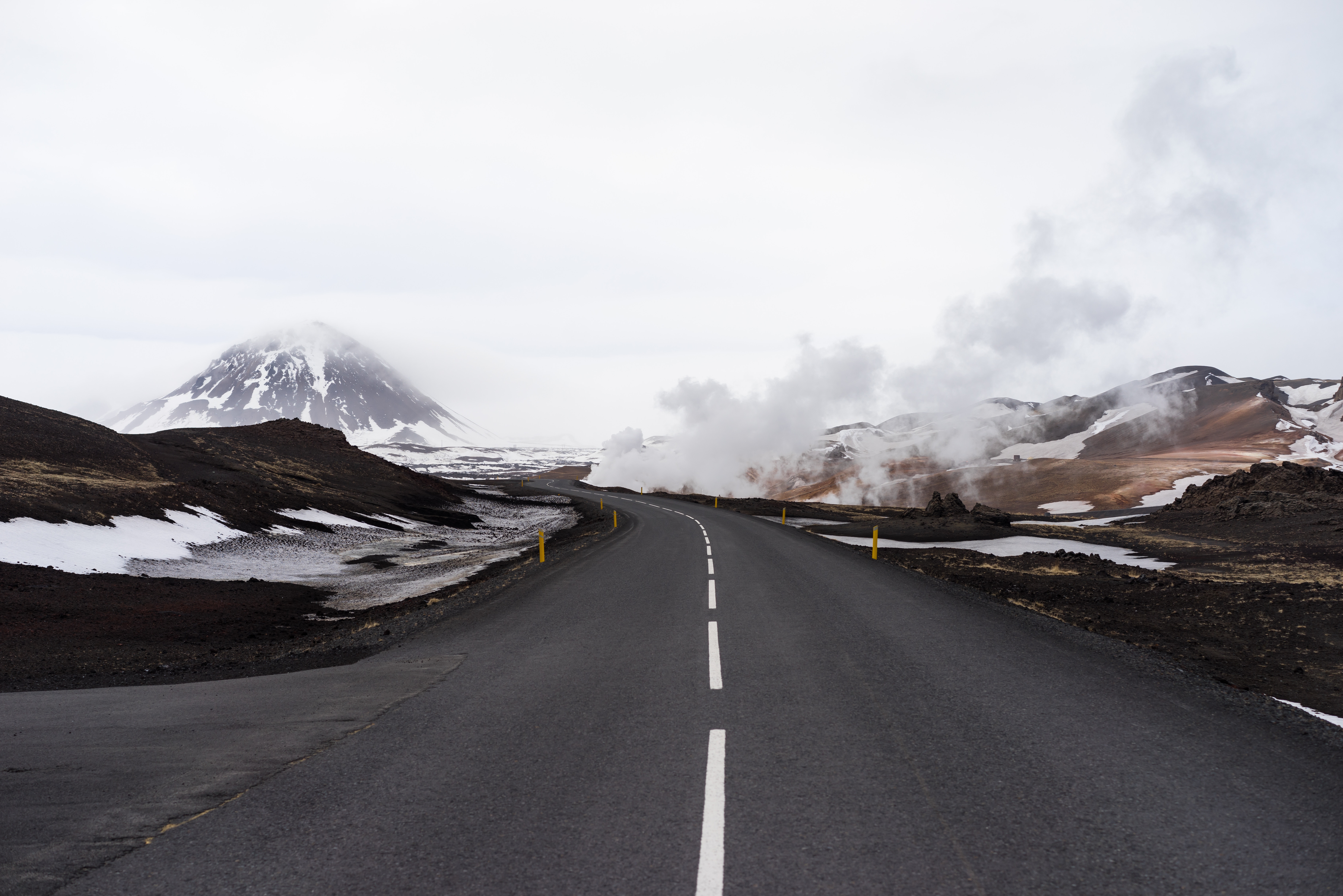 Road through Iceland with snow-capped mountains and steam HD Wallpaper