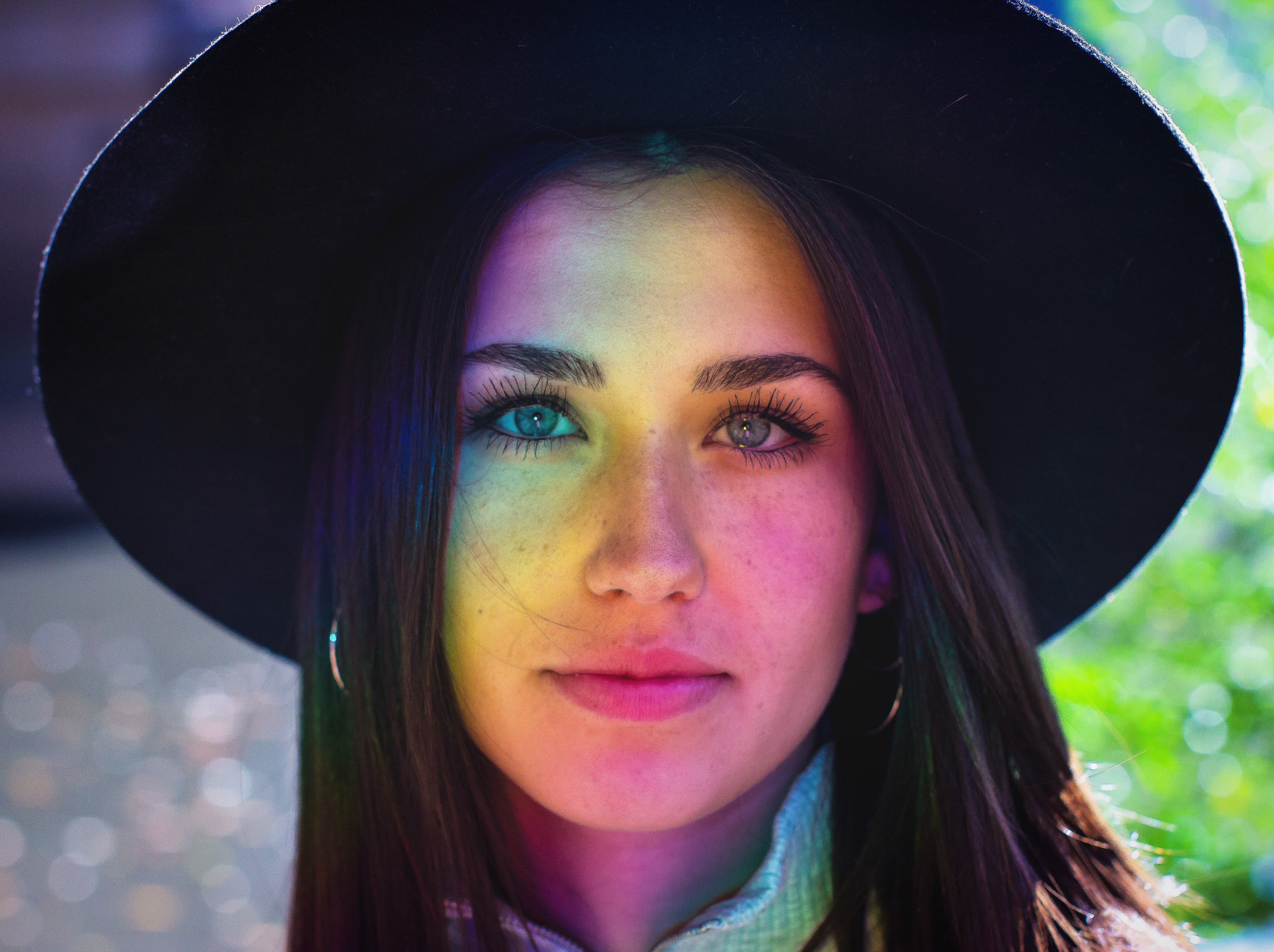 Woman wearing a hat with rainbow light on her face HD Wallpaper