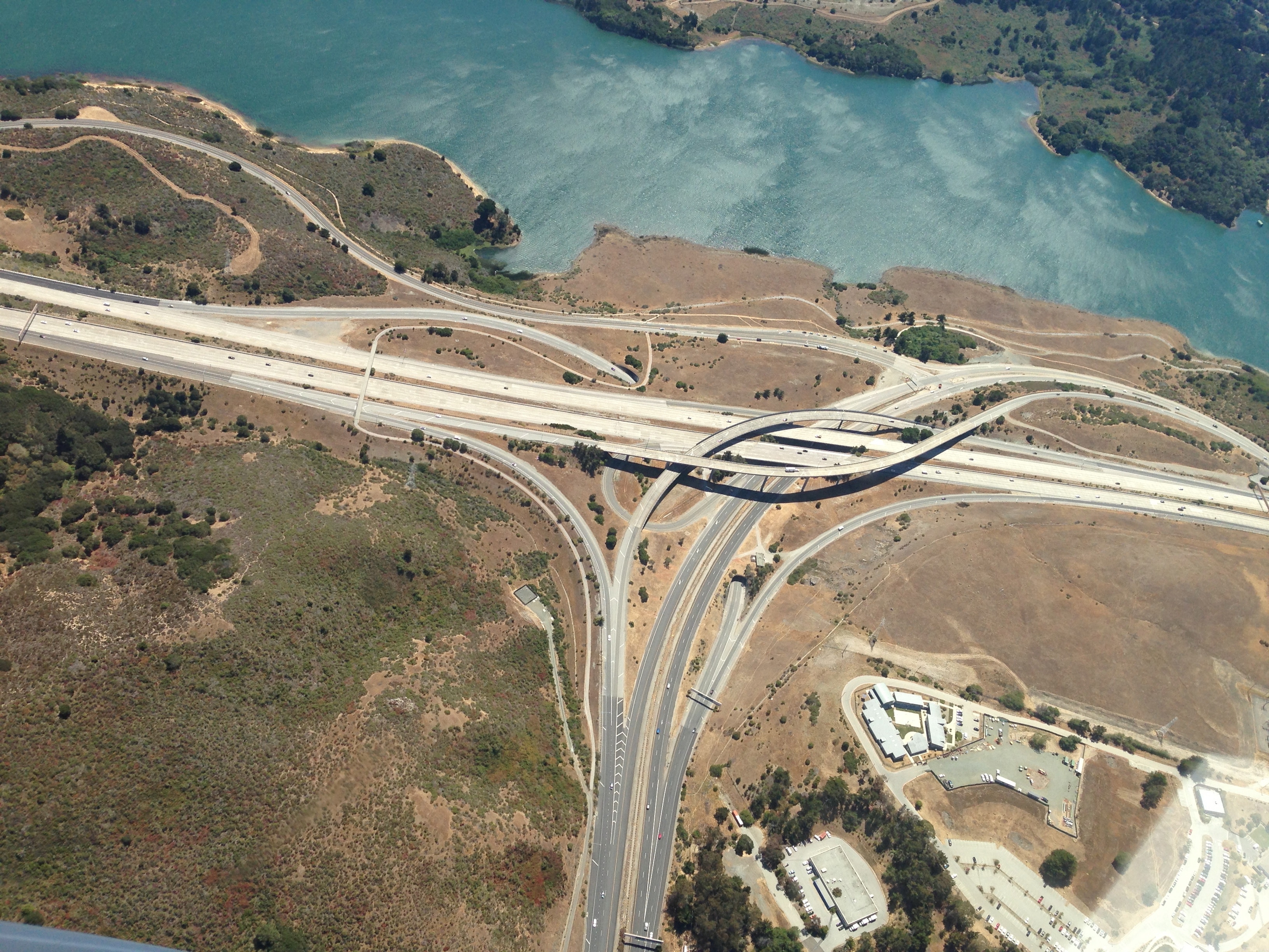 Aerial view of a highway interchange near a body of water HD Wallpaper