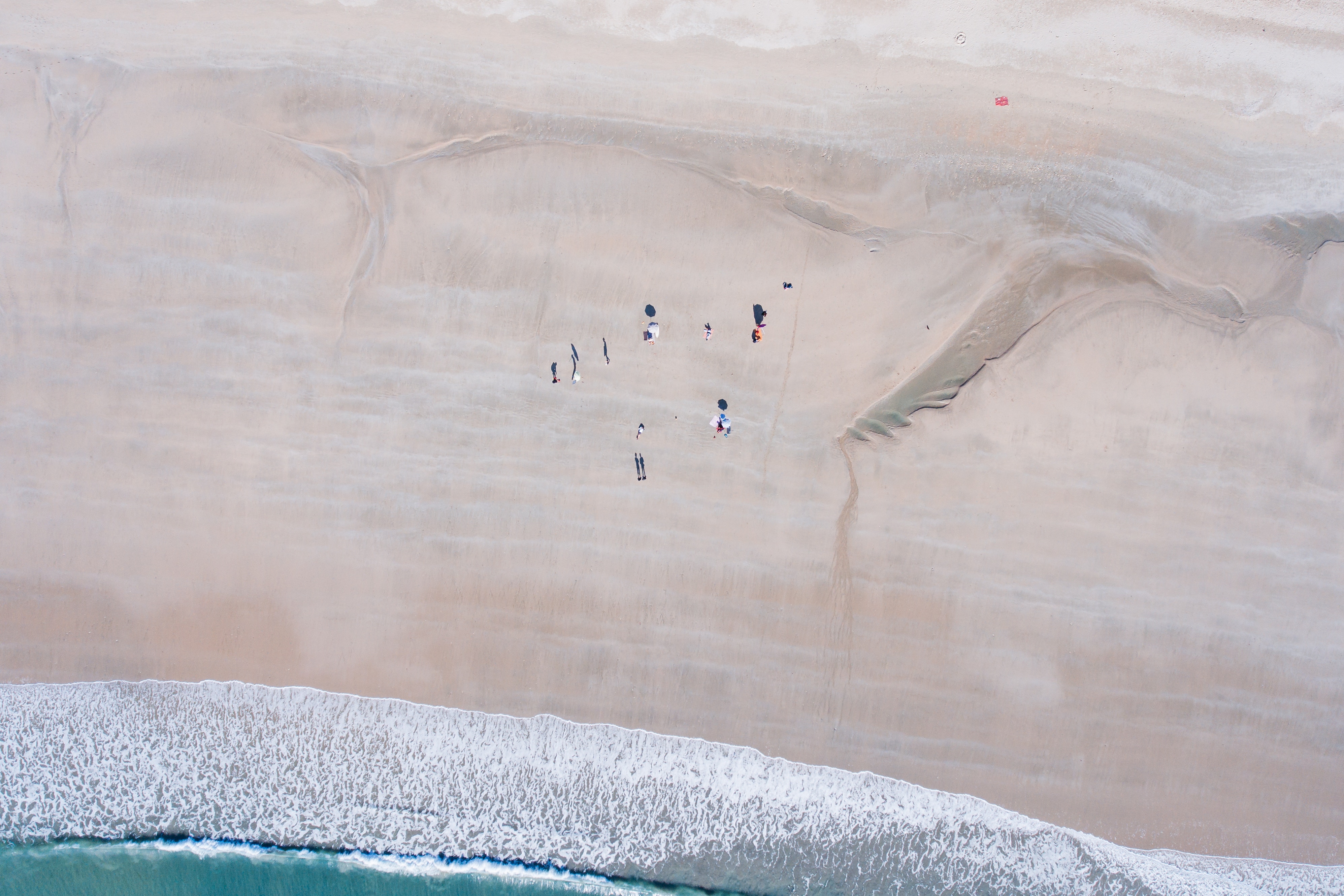 Aerial view of people on a sandy beach with waves HD Wallpaper