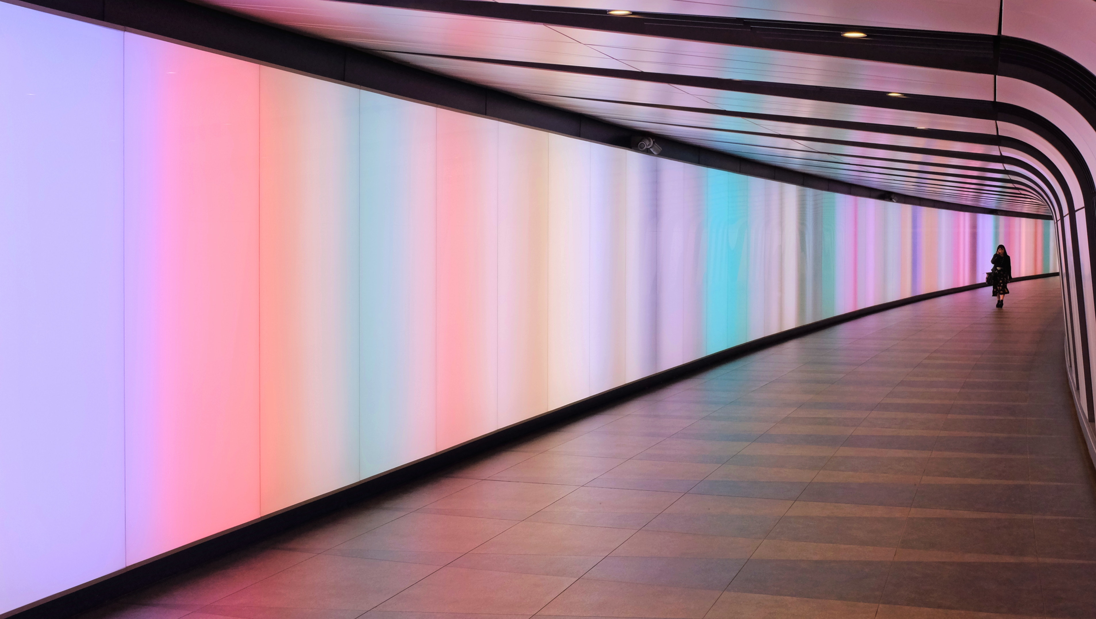 Person walking through illuminated tunnel at King's Cross HD Wallpaper