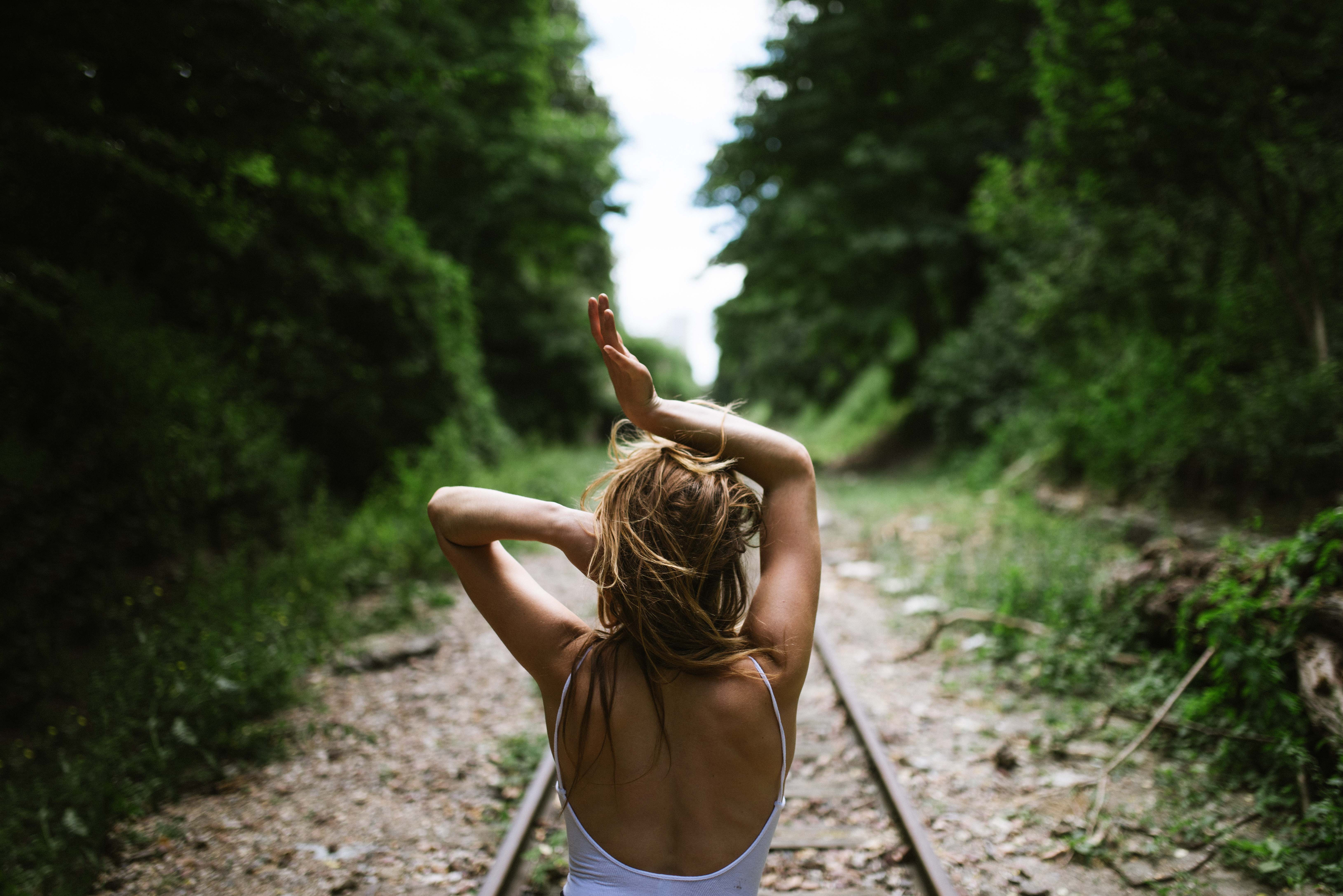 Woman dancing on railway tracks surrounded by trees HD Wallpaper