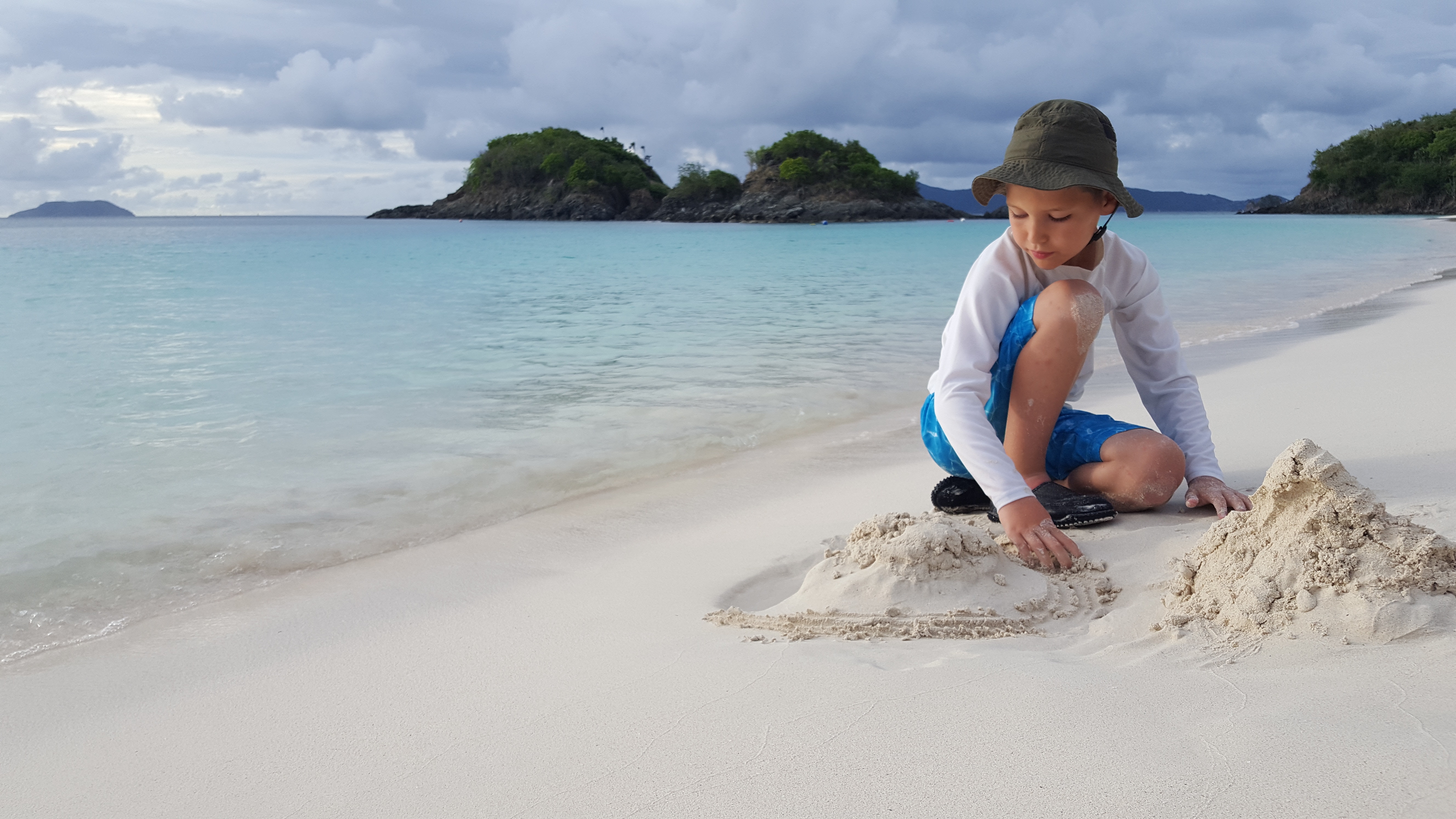 Boy playing with sand on a tropical beach HD Wallpaper