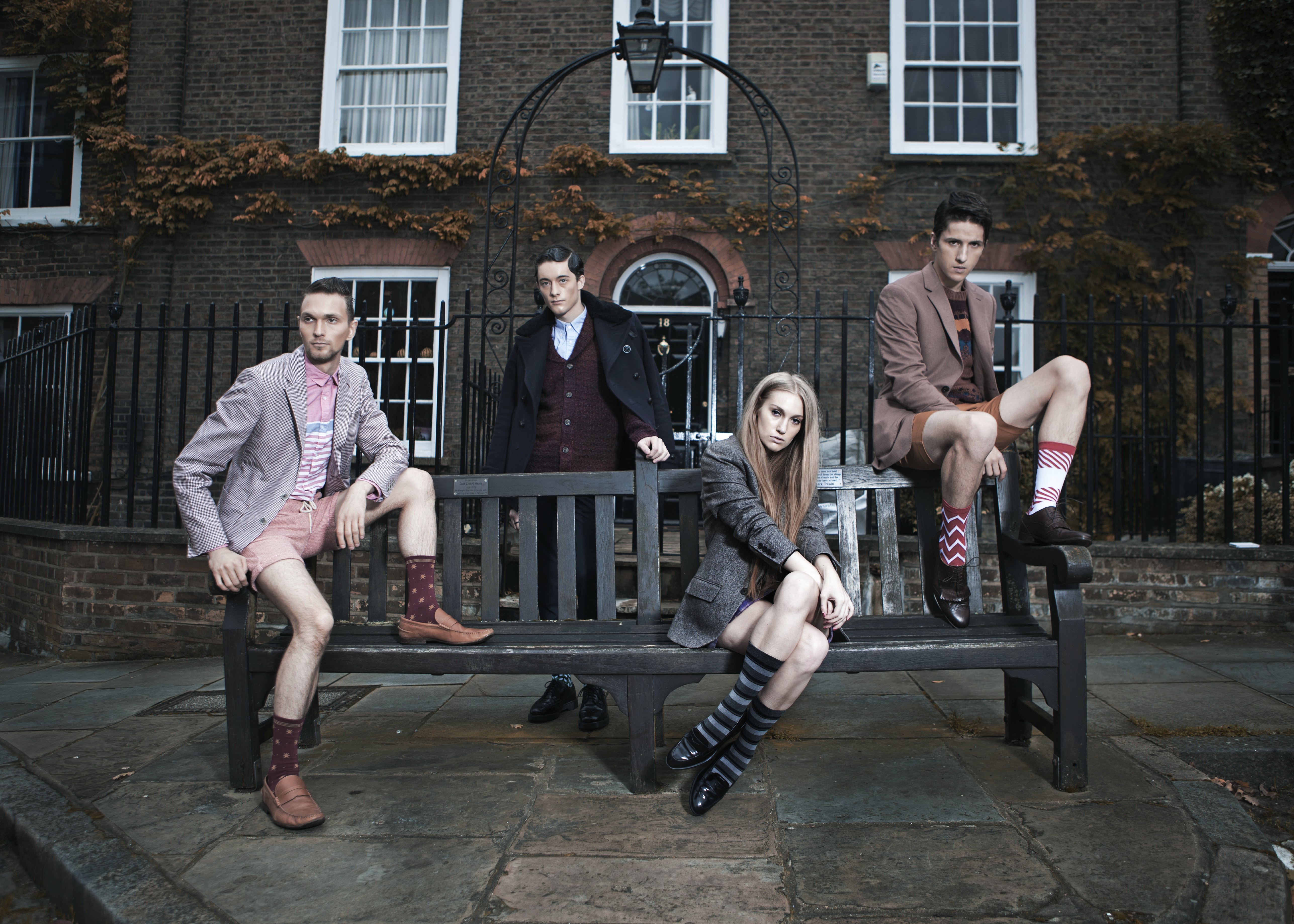Four people posing on a bench in front of a building HD Wallpaper