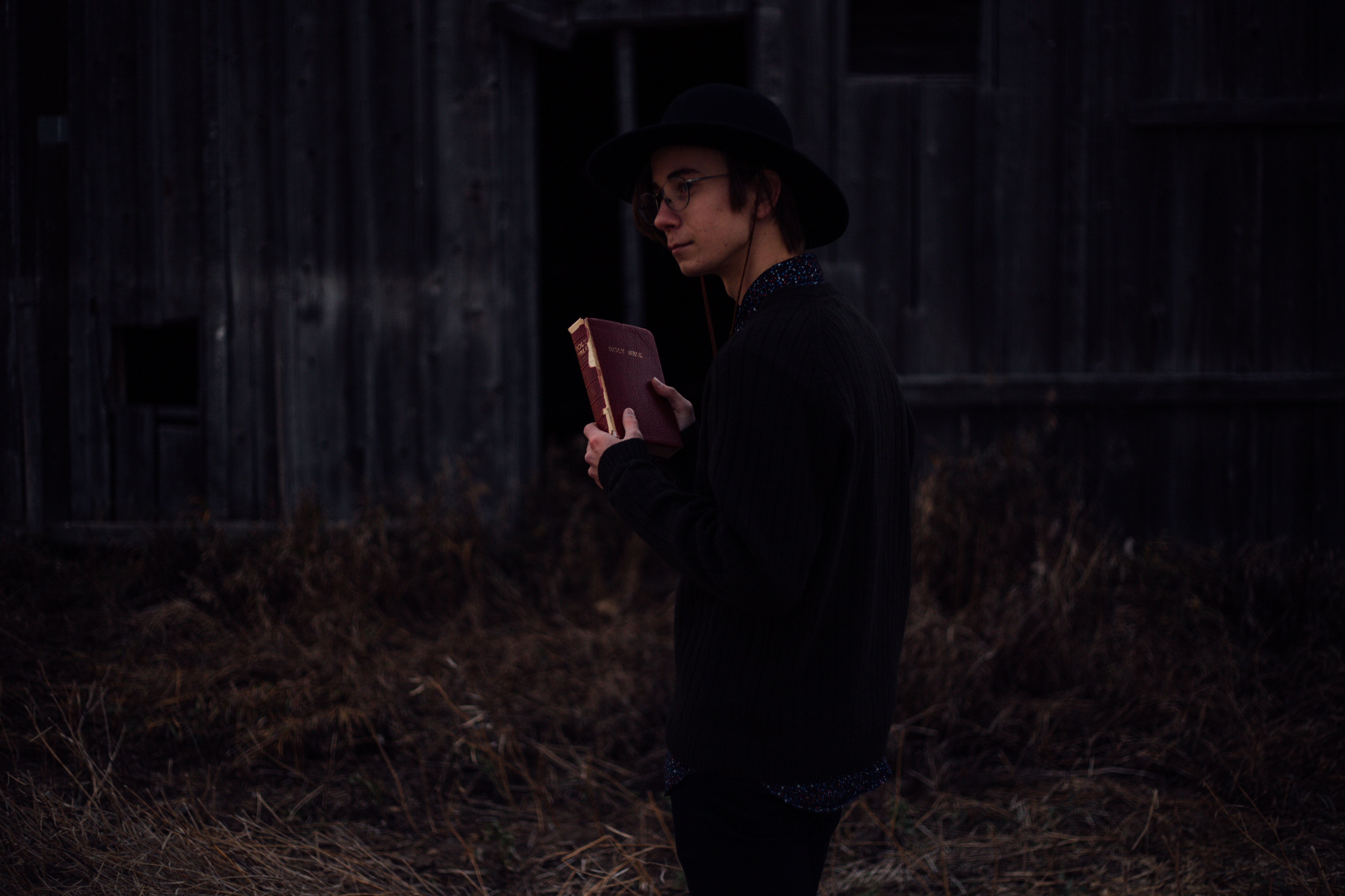 Man in hat holding a bible outdoors HD Wallpaper