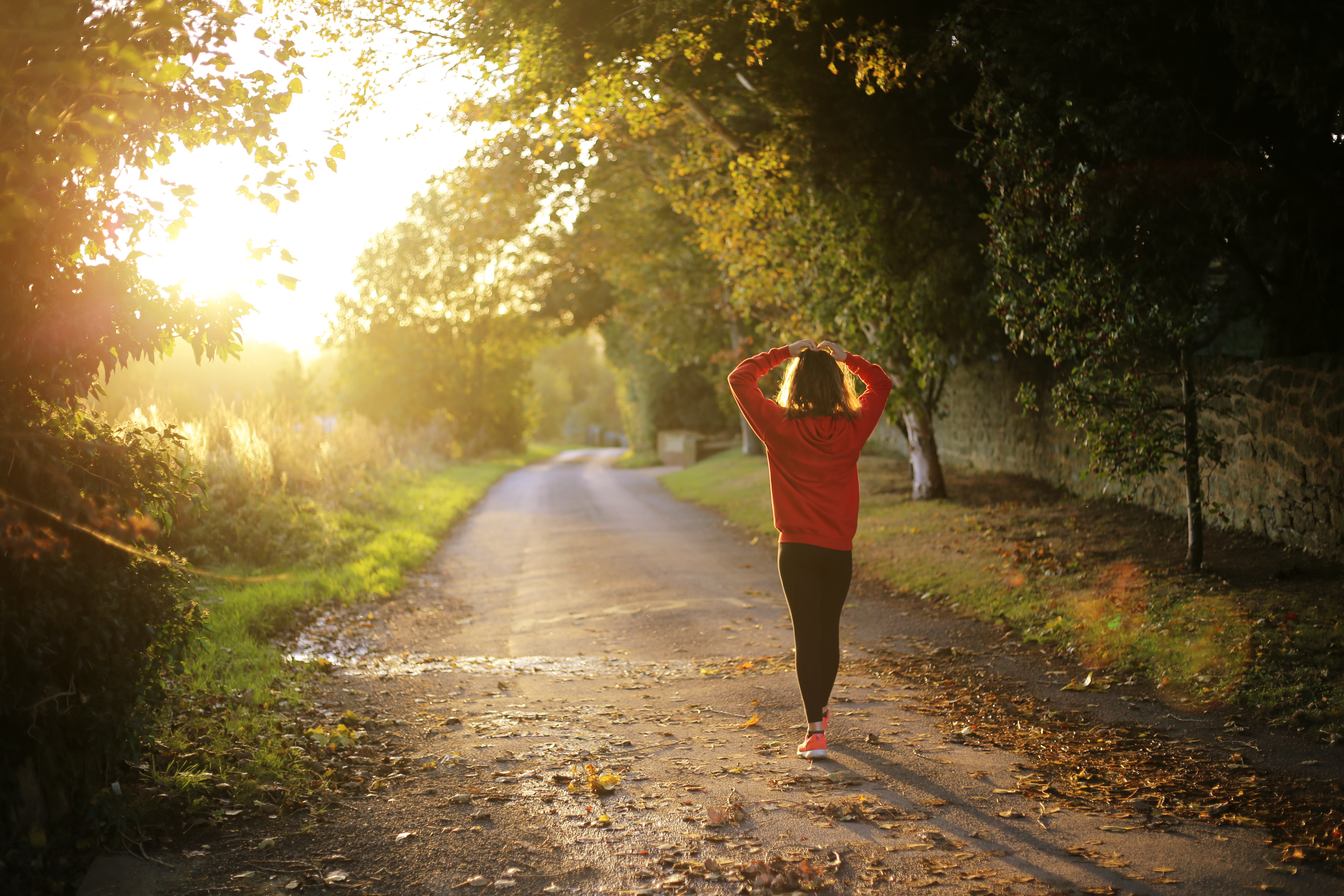 Woman in red hoodie walking on a country road at sunset HD Wallpaper