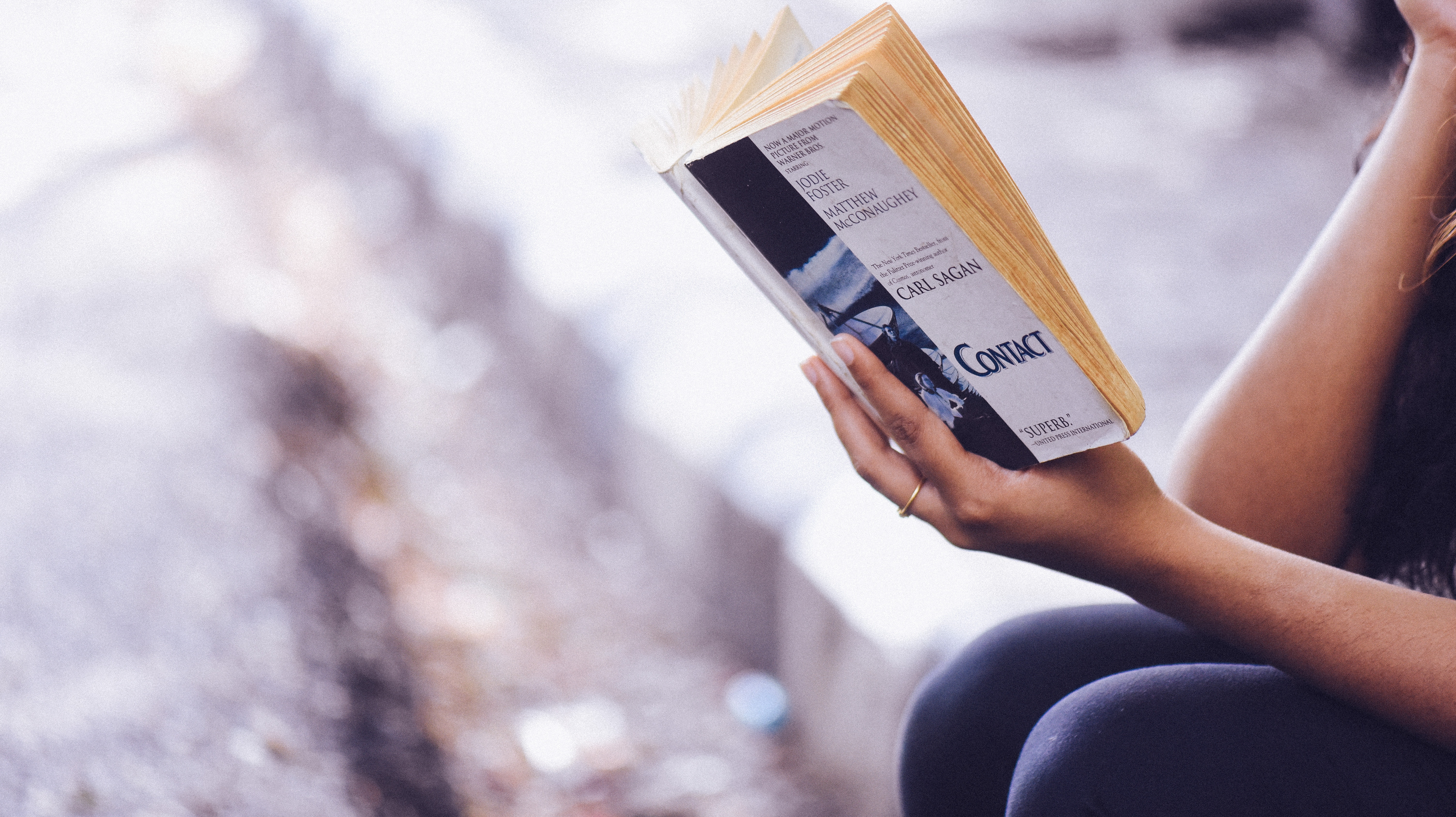Person reading Carl Sagan's Contact novel HD Wallpaper