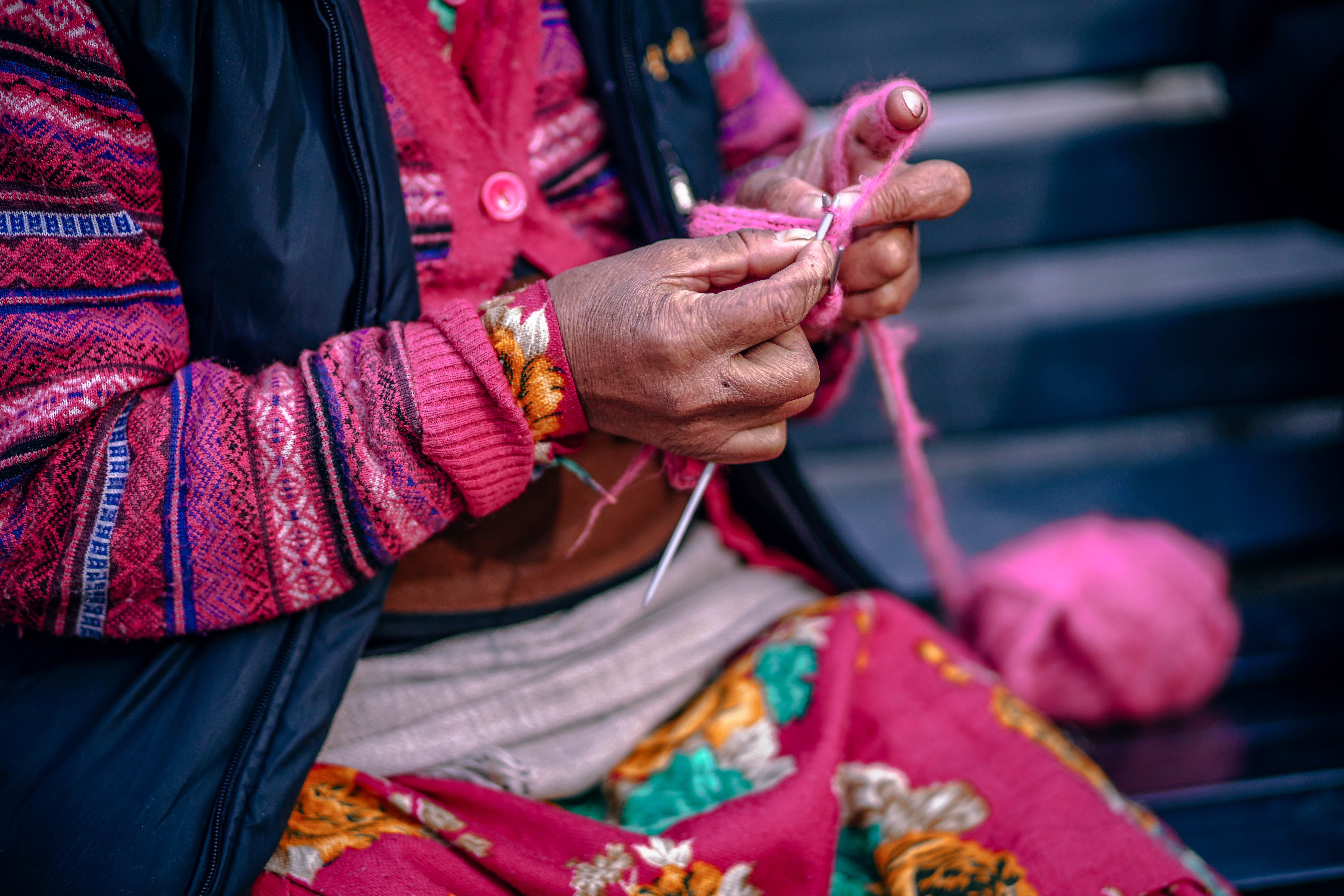 Person knitting with pink yarn and needles HD Wallpaper