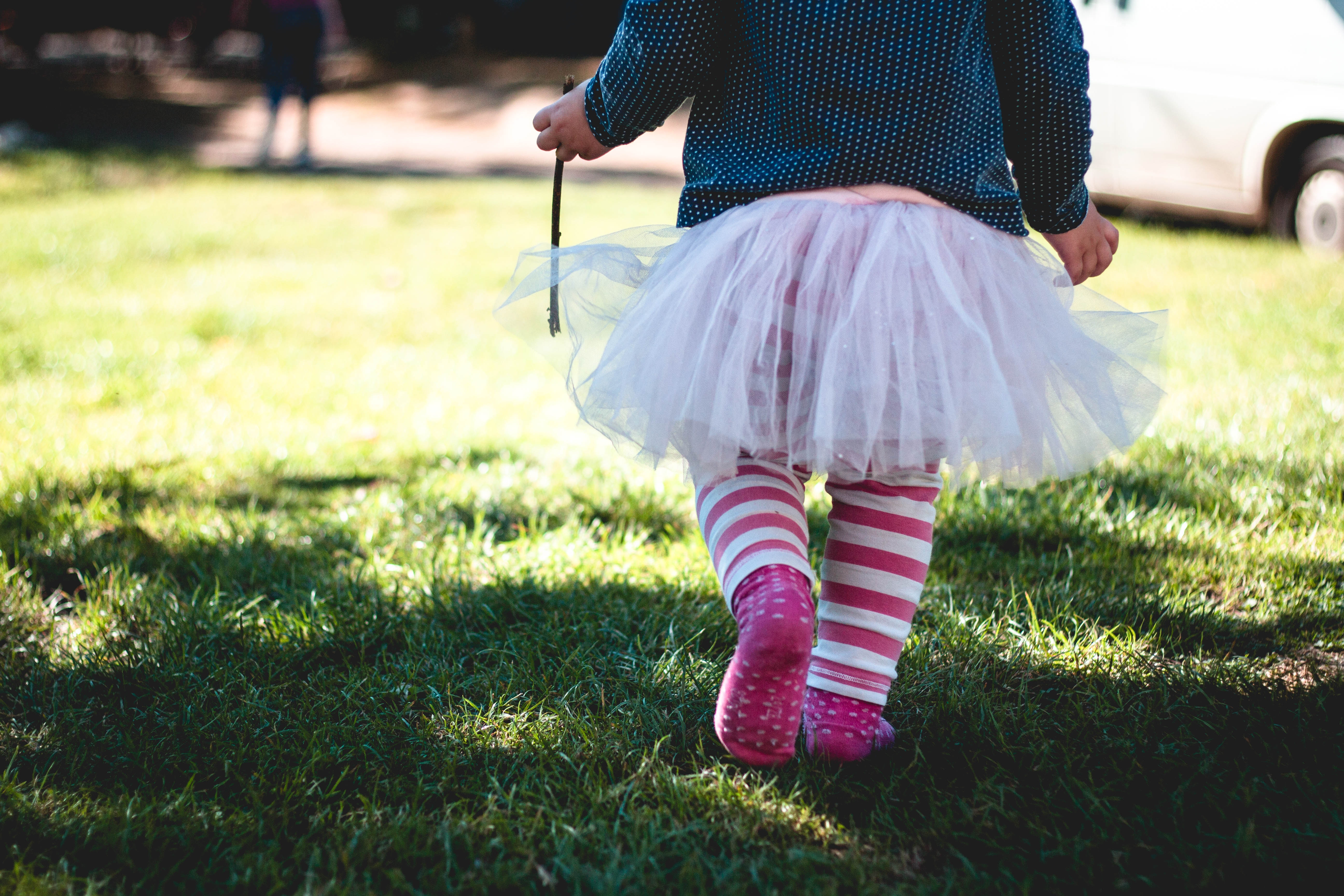 Child in tutu and striped socks walking on grass HD Wallpaper