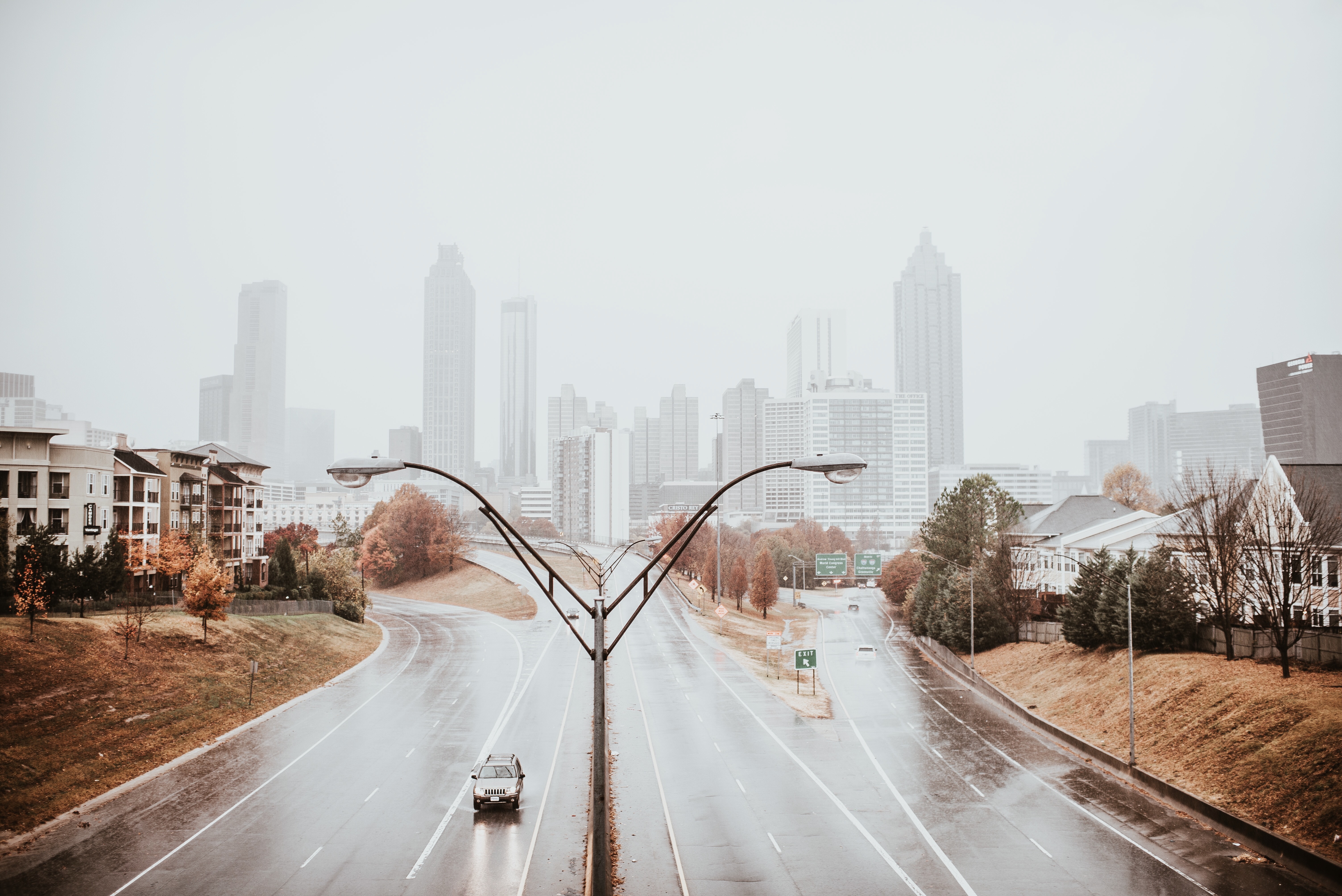 Rainy city skyline with a car on the freeway HD Wallpaper