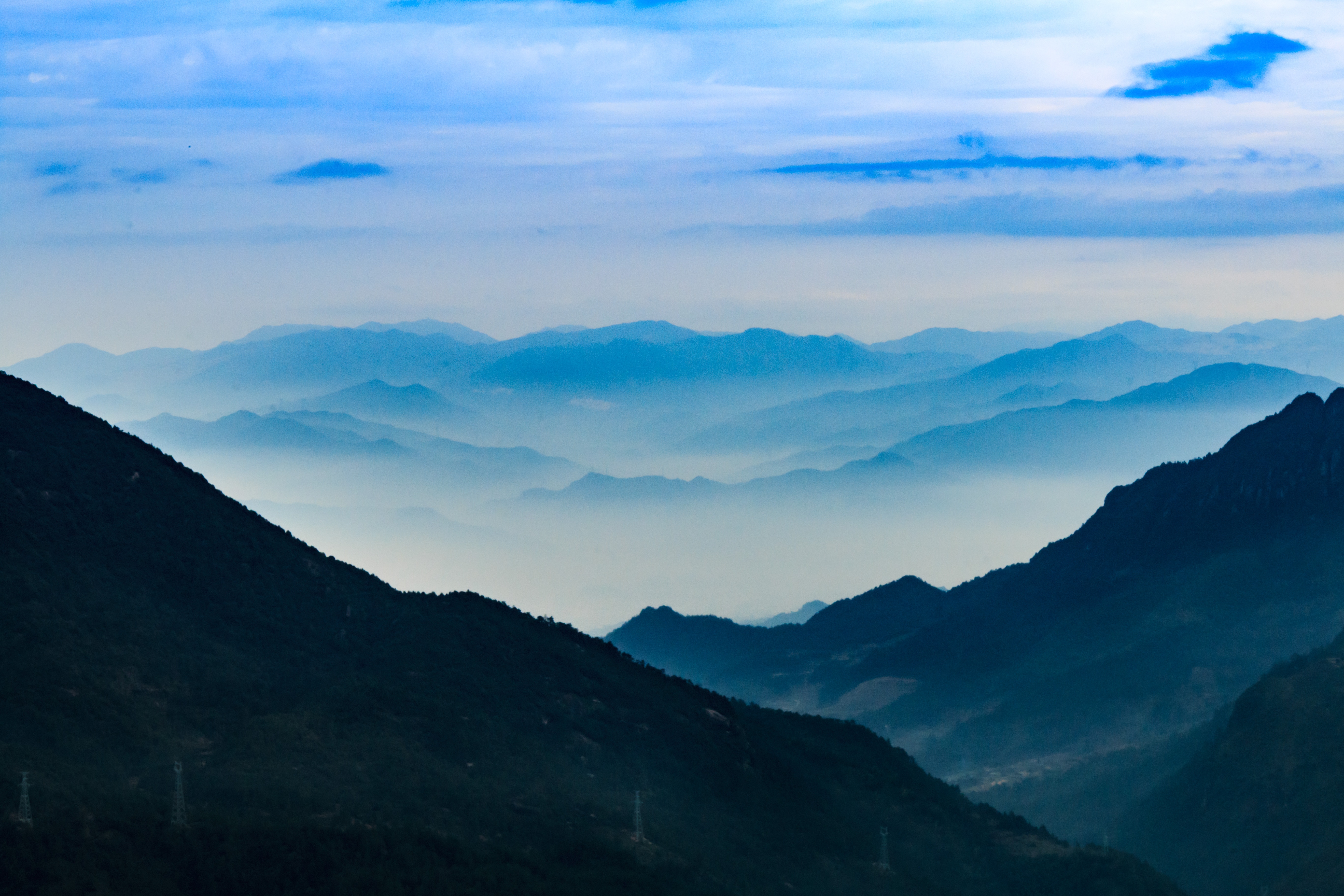 Blue mountains shrouded in mist under a cloudy sky HD Wallpaper
